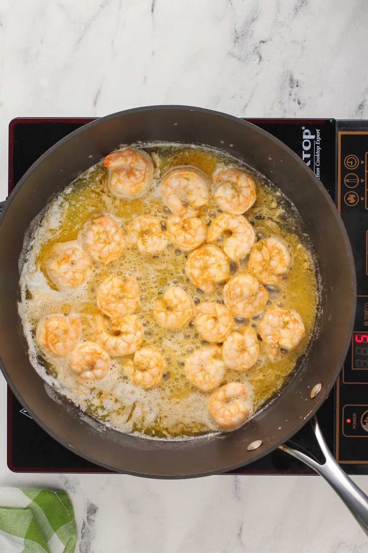 Shrimp being cooked in butter in a pan.