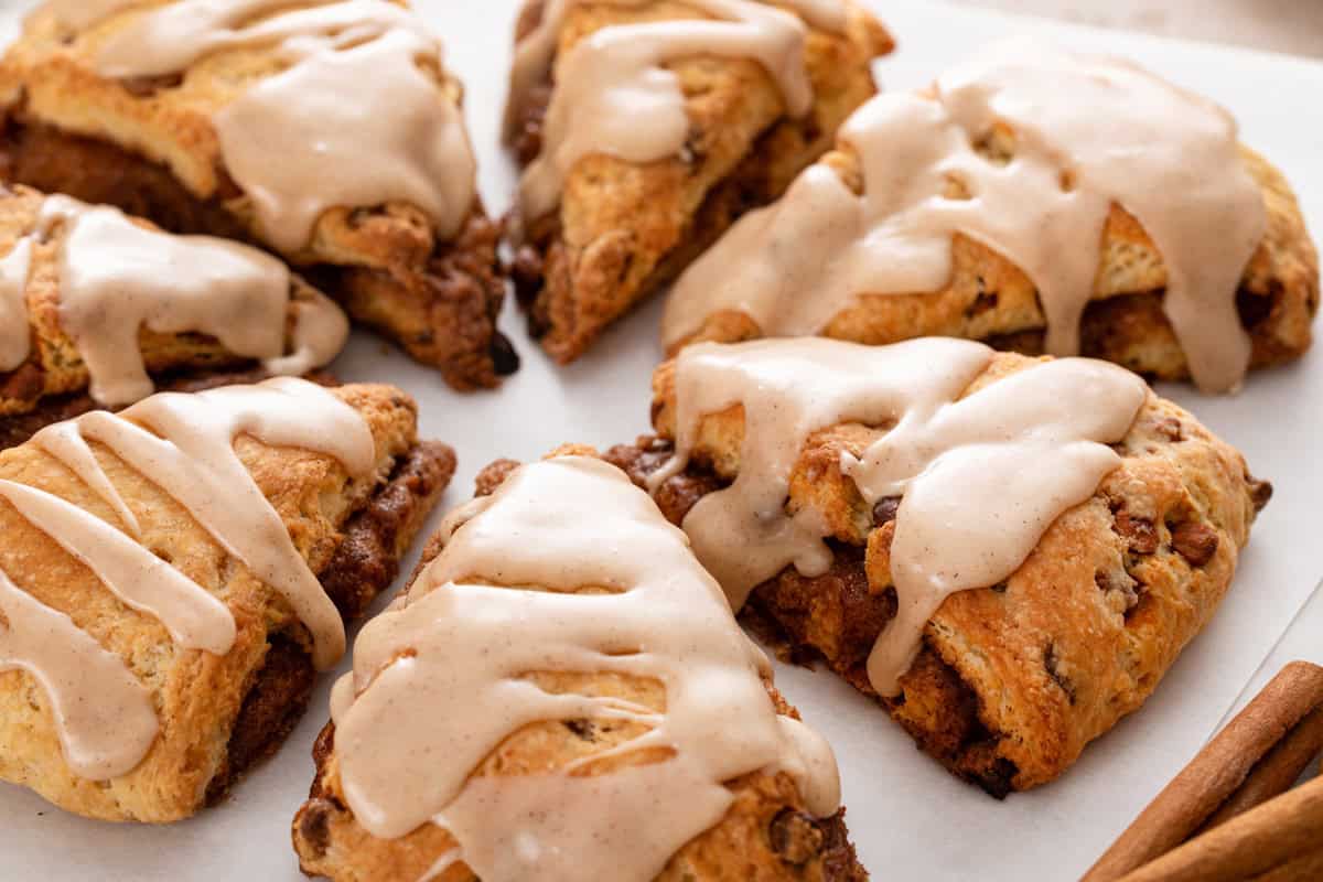 Glazed cinnamon scones arranged on a piece of parchment paper.