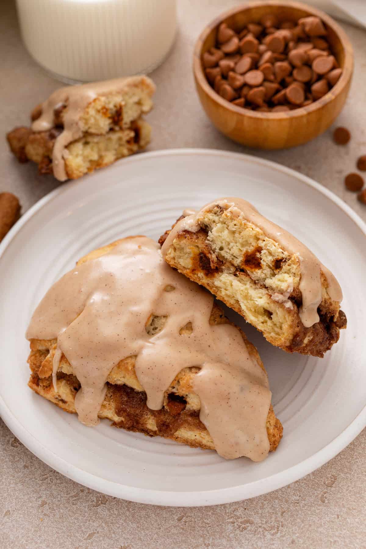 Halved cinnamon scone next to a full scone on a white plate.