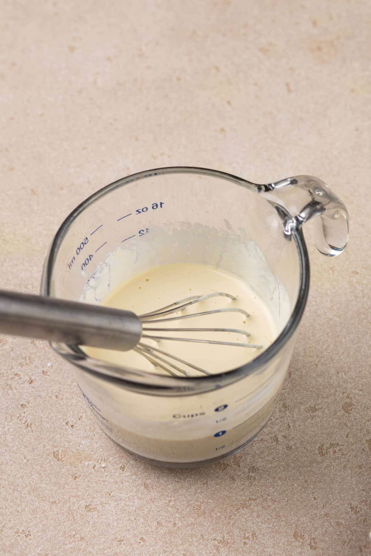 Wet ingredients for cinnamon scones whisked in a measuring cup.