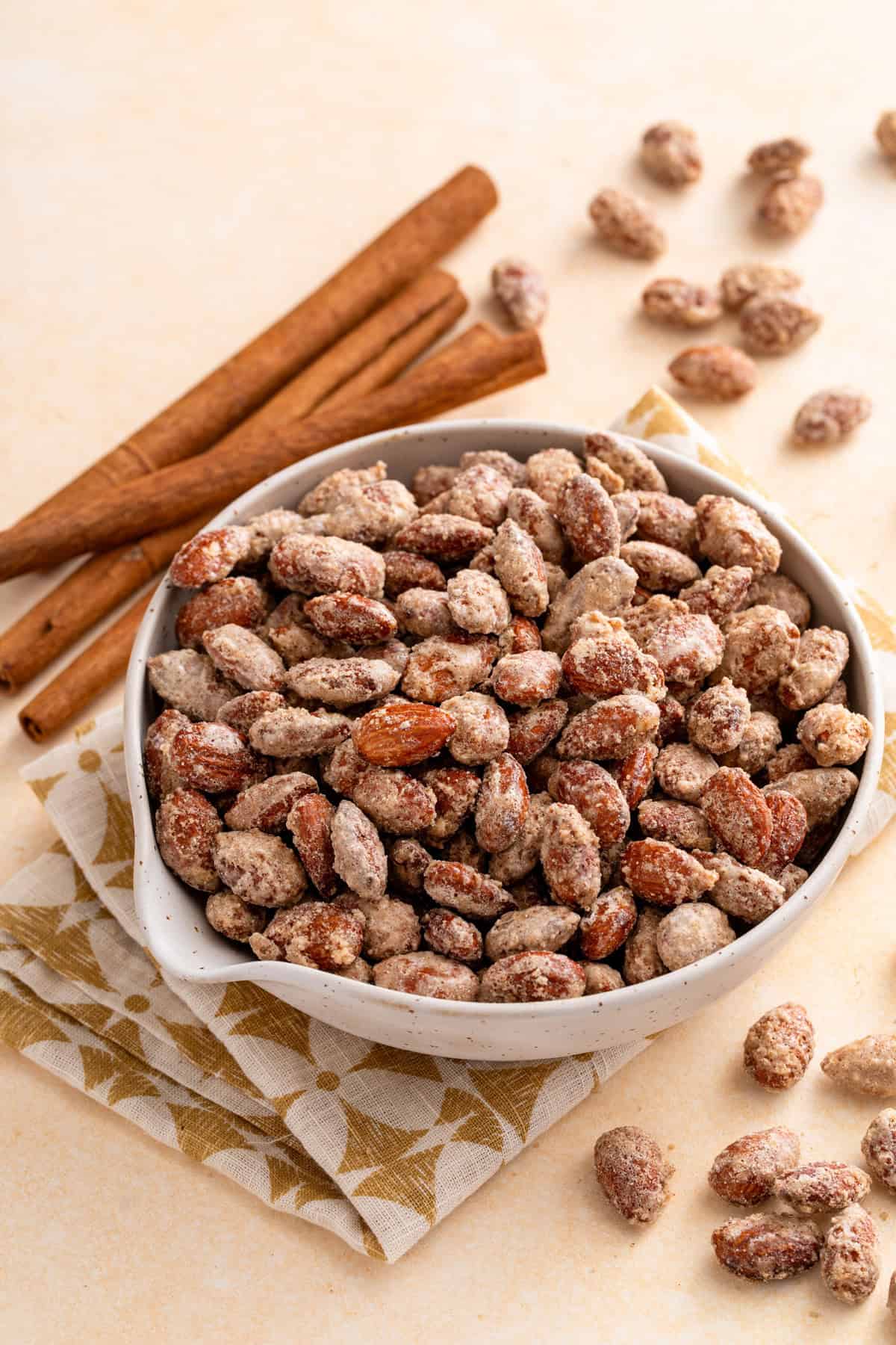 White bowl filled with candied almonds on a countertop.