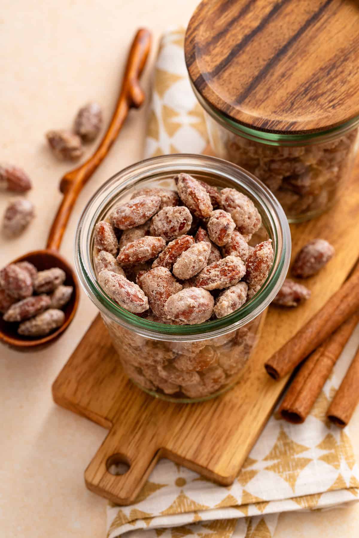 Candied almonds in a glass jar set on a wooden board.