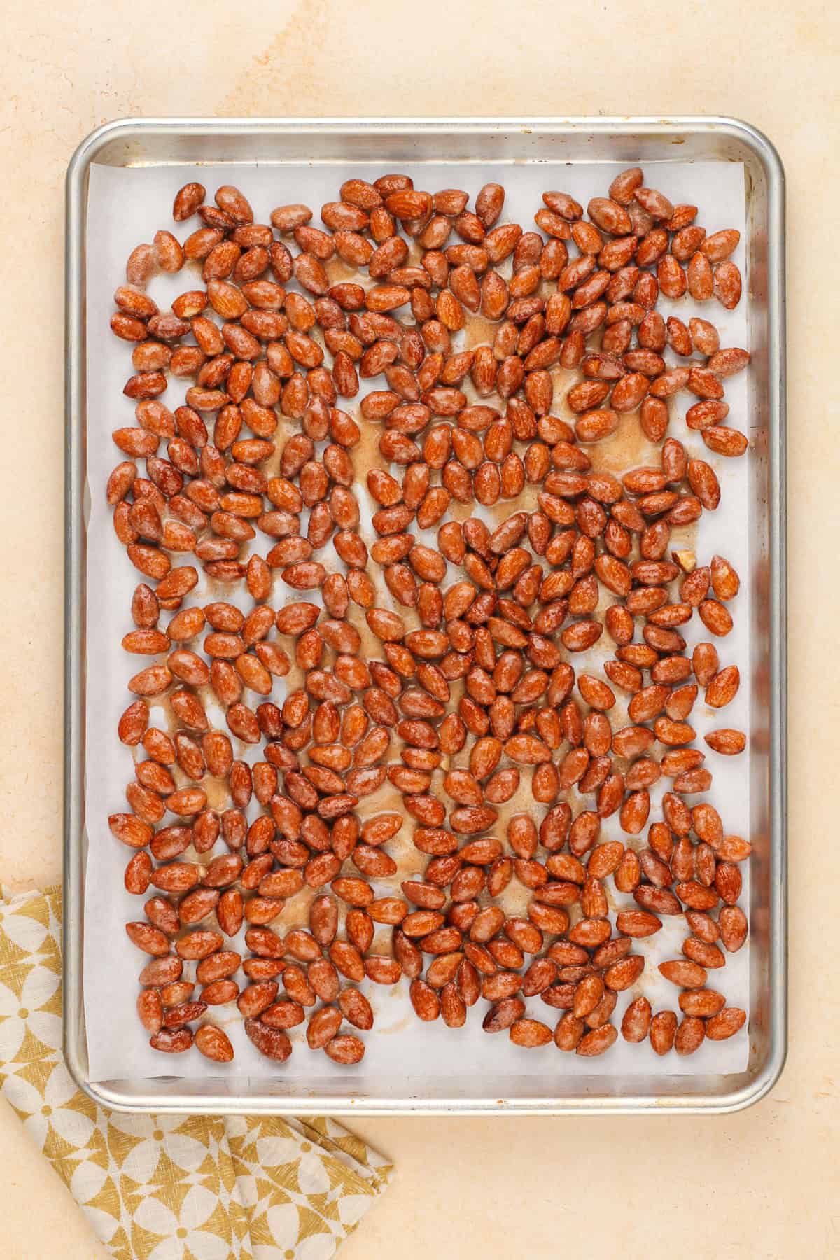 Unbaked candied almonds spread on a sheet pan, ready to go in the oven.