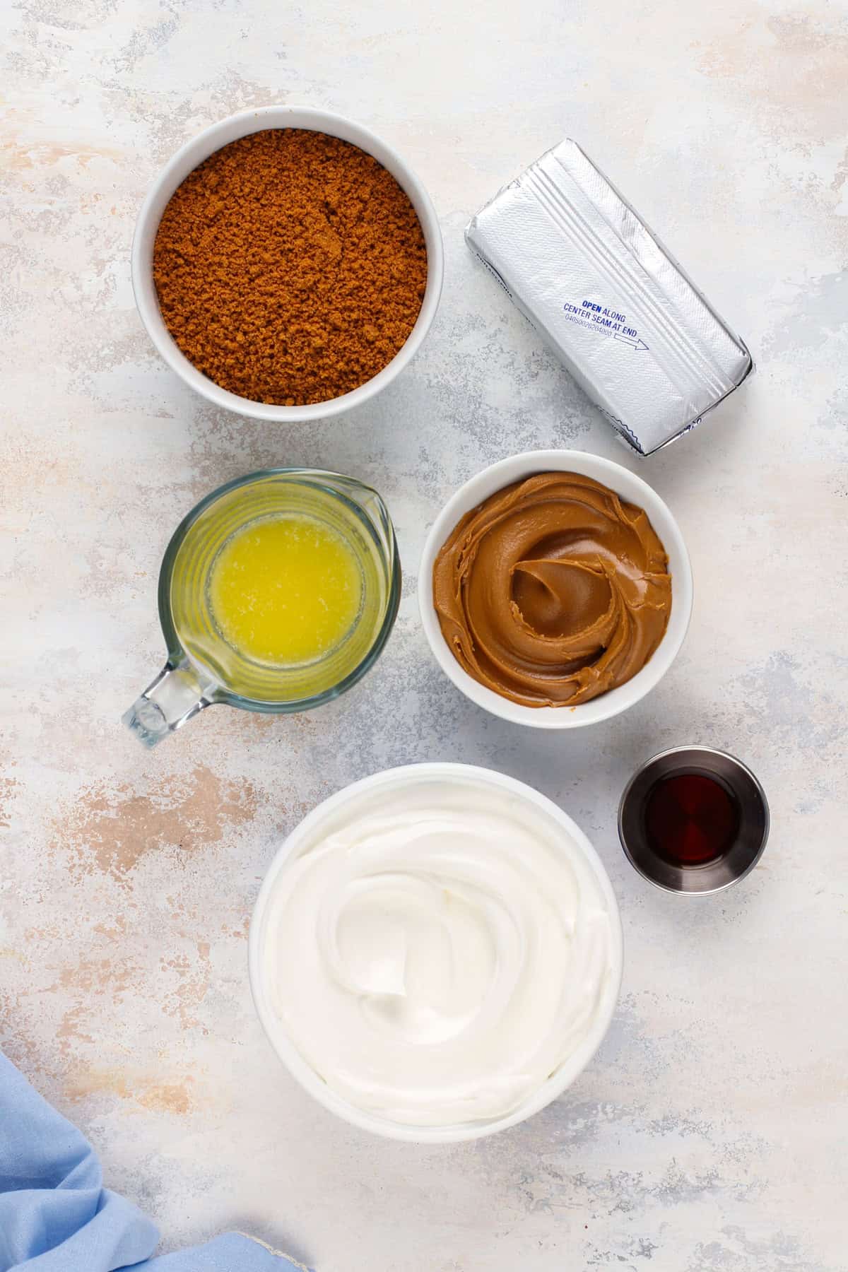 Ingredients for no-bake biscoff cheesecake arranged on a countertop.