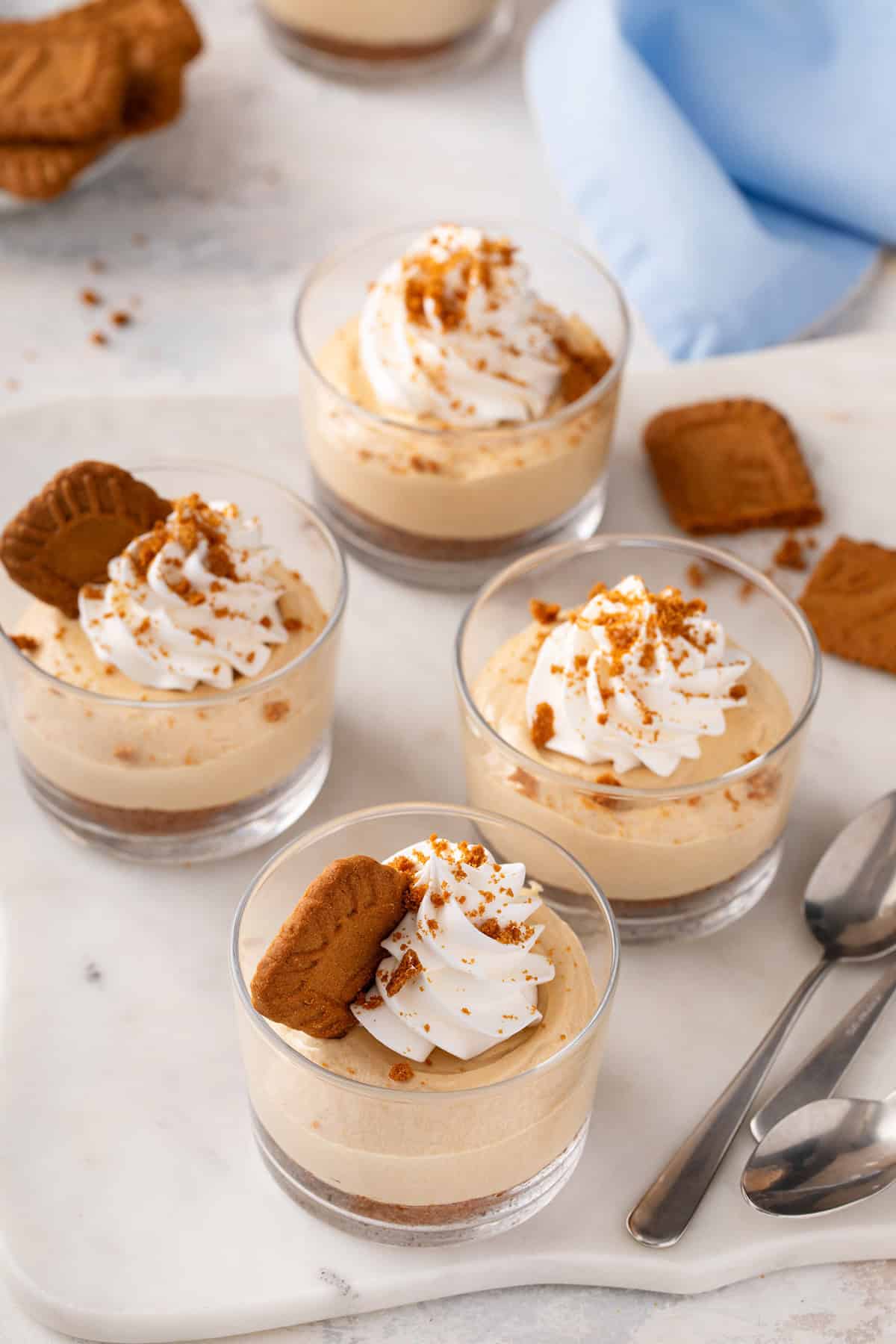 Four ramekins of no-bake biscoff cheesecake arranged on a marble board.