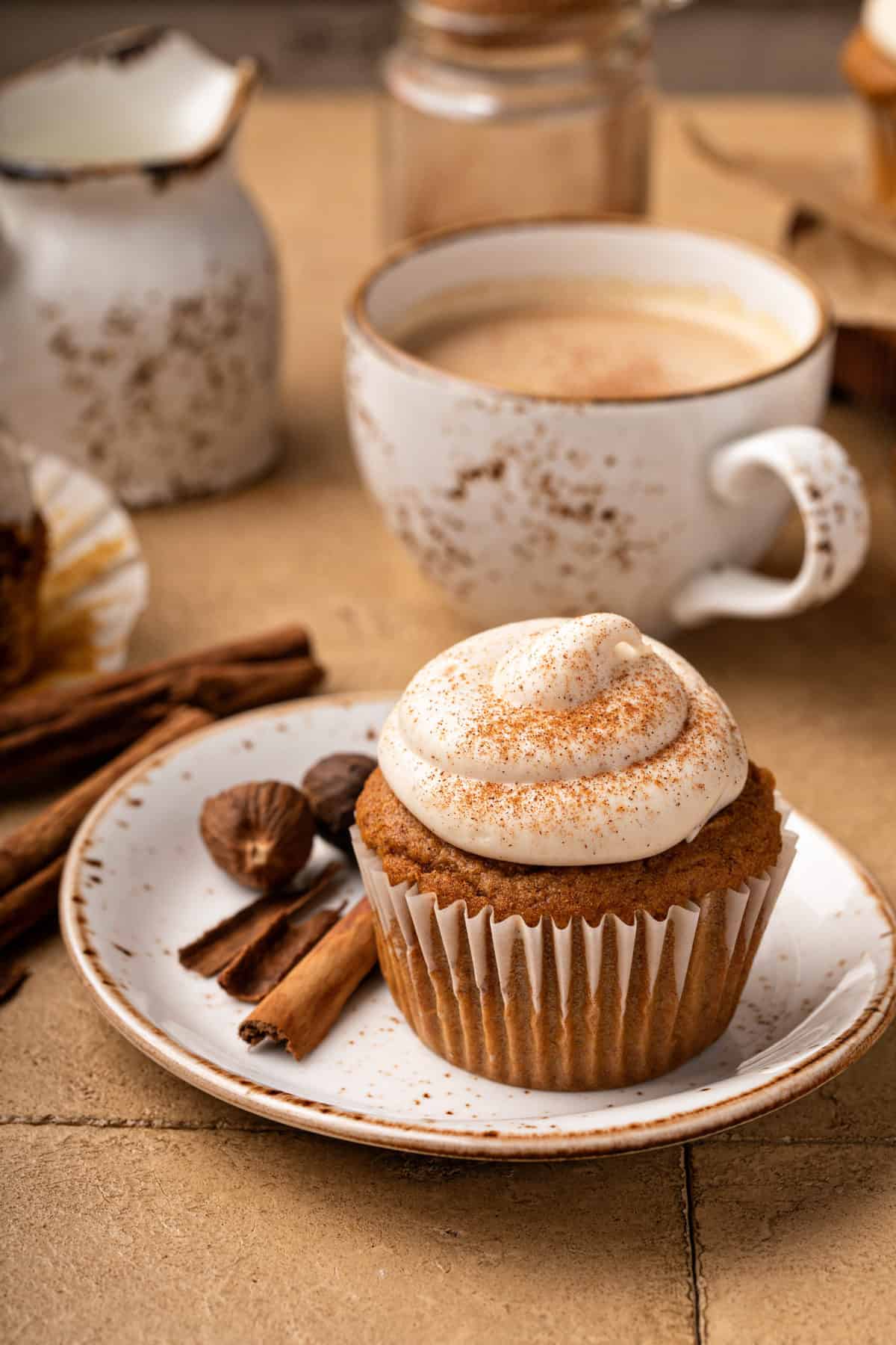 Plated pumpkin spice cupcake with a cup of coffee in the background
