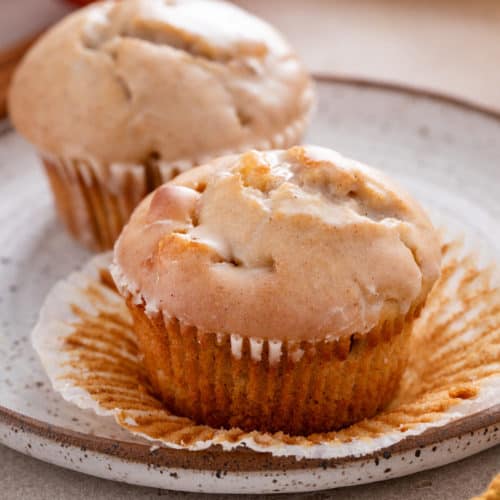 Close up image of an unwrapped apple cider donut muffin on a plate.