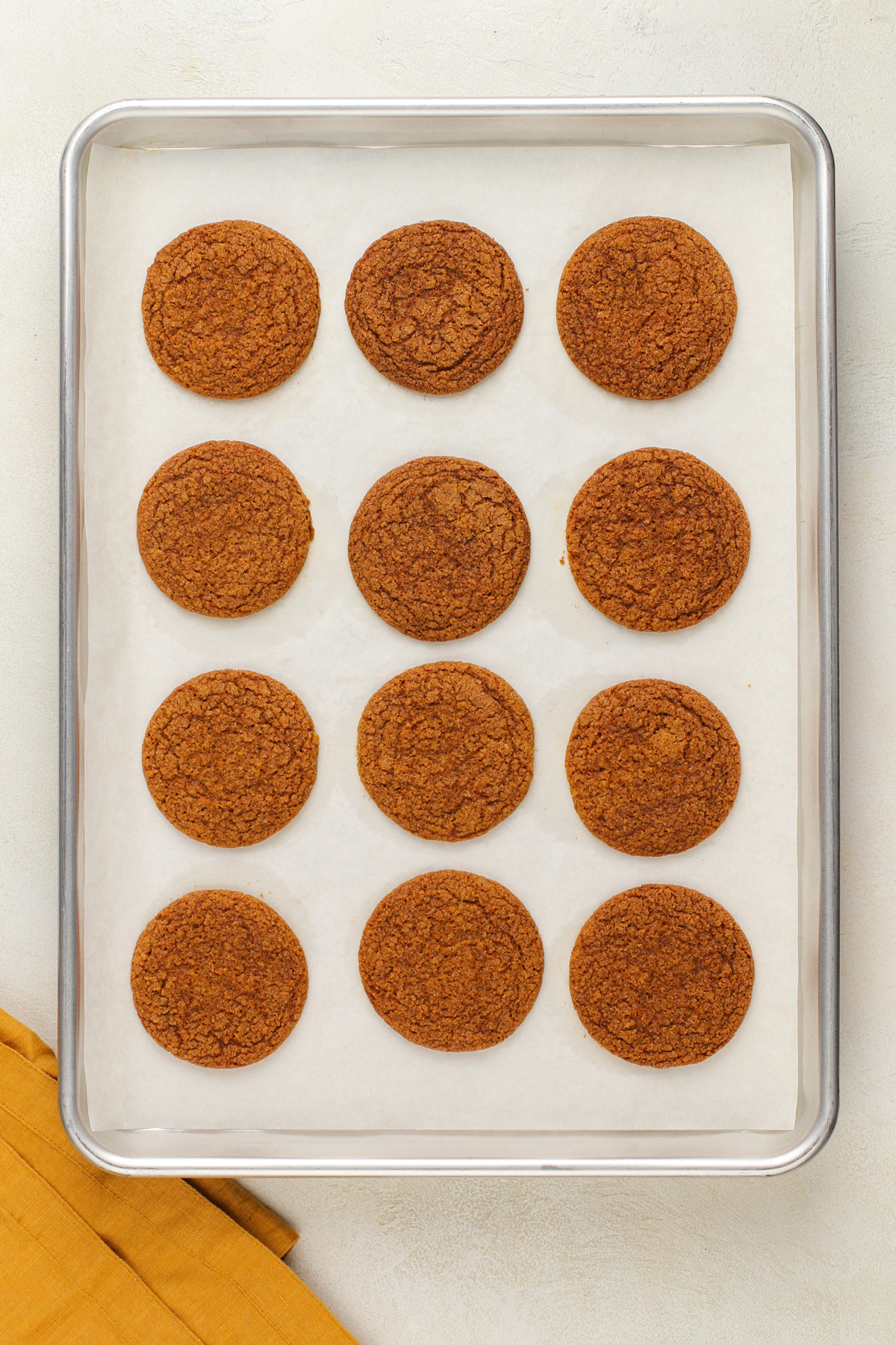 Baked molasses cookies on a parchment-lined sheet pan.