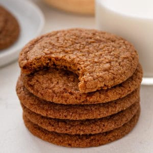 Bite taken from a chewy molasses cookie stacked on other cookies.