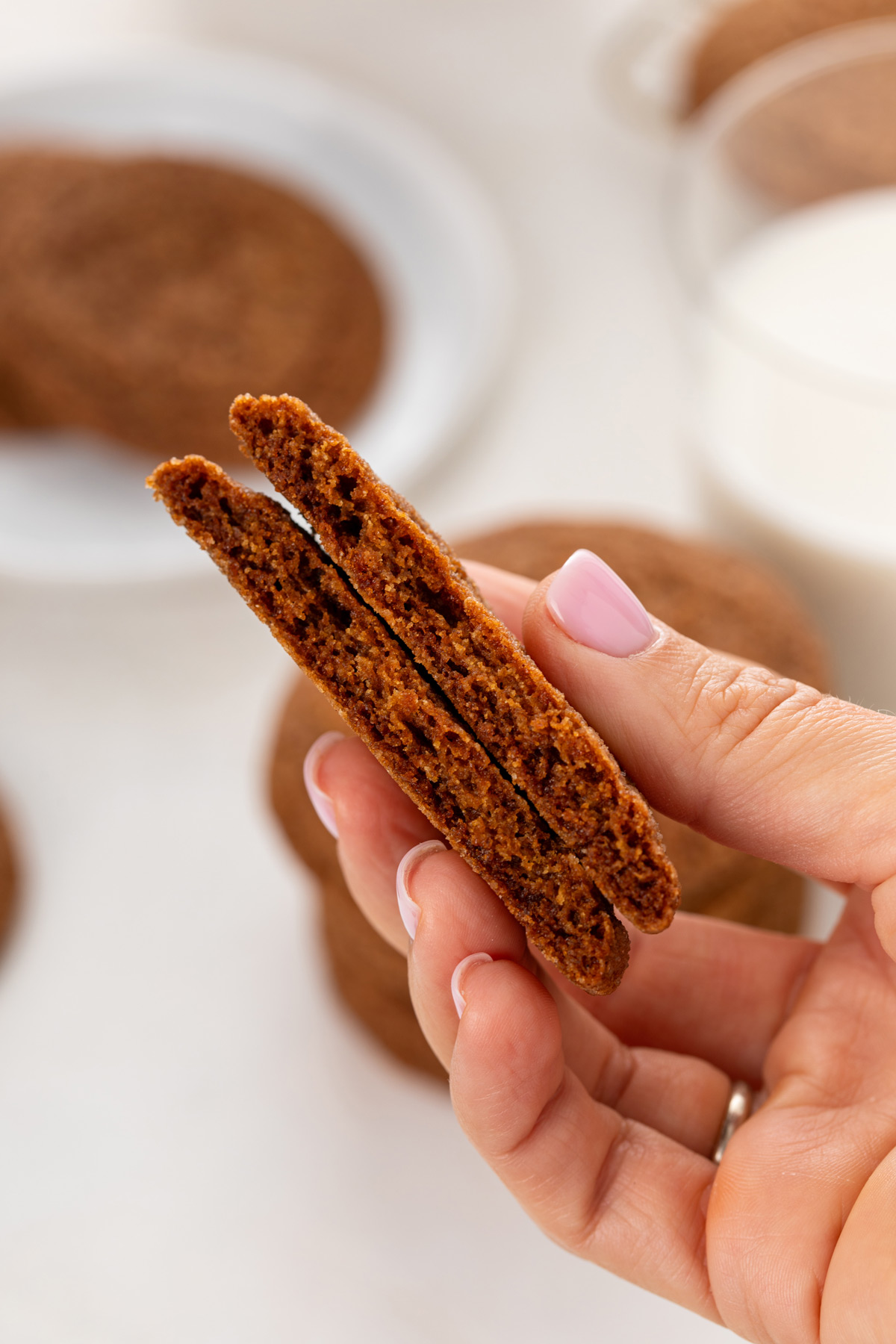 Hand holding up a molasses cookie broken in half.