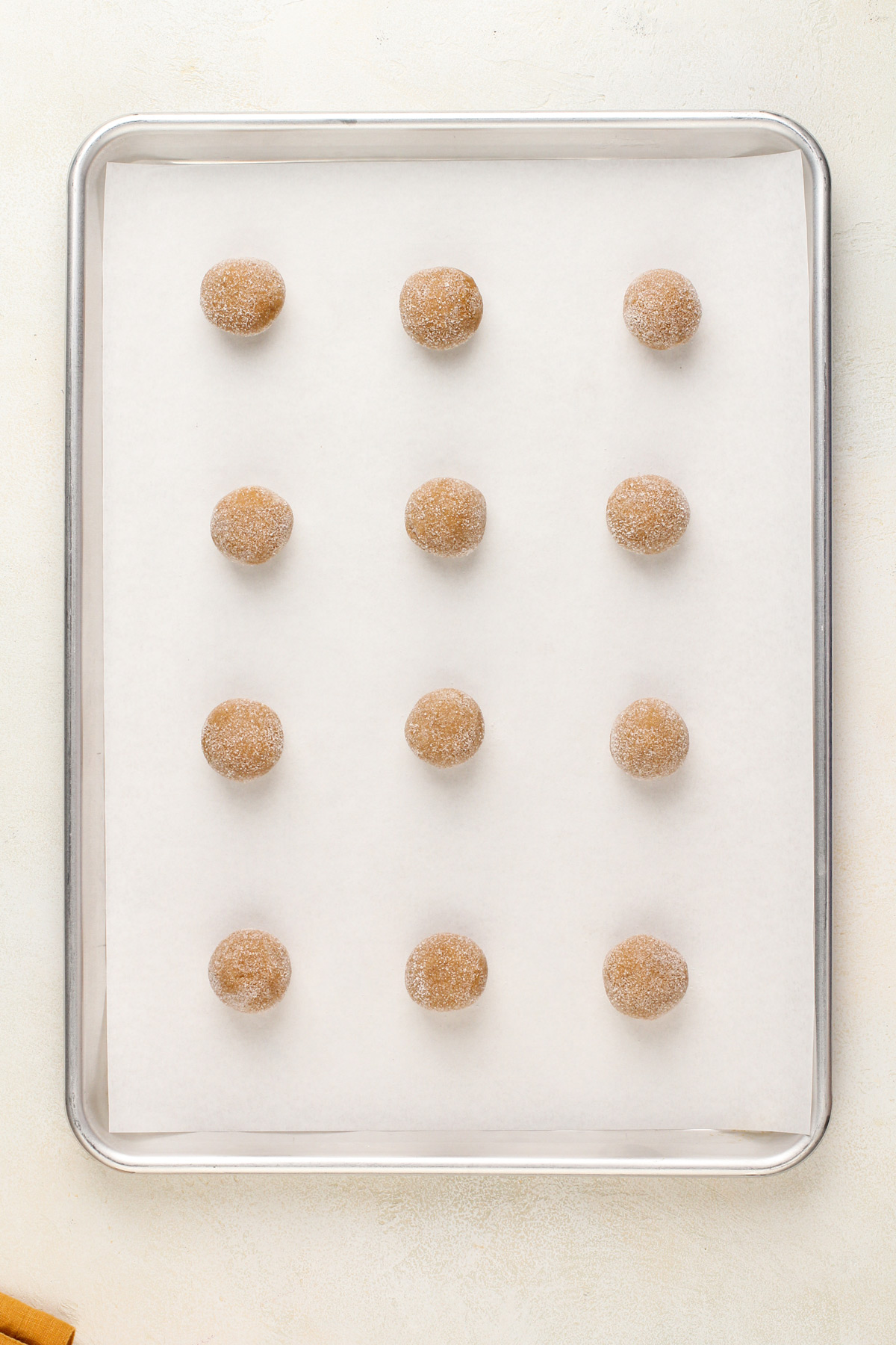 Unbaked molasses cookies arranged on a parchment-lined baking sheet.