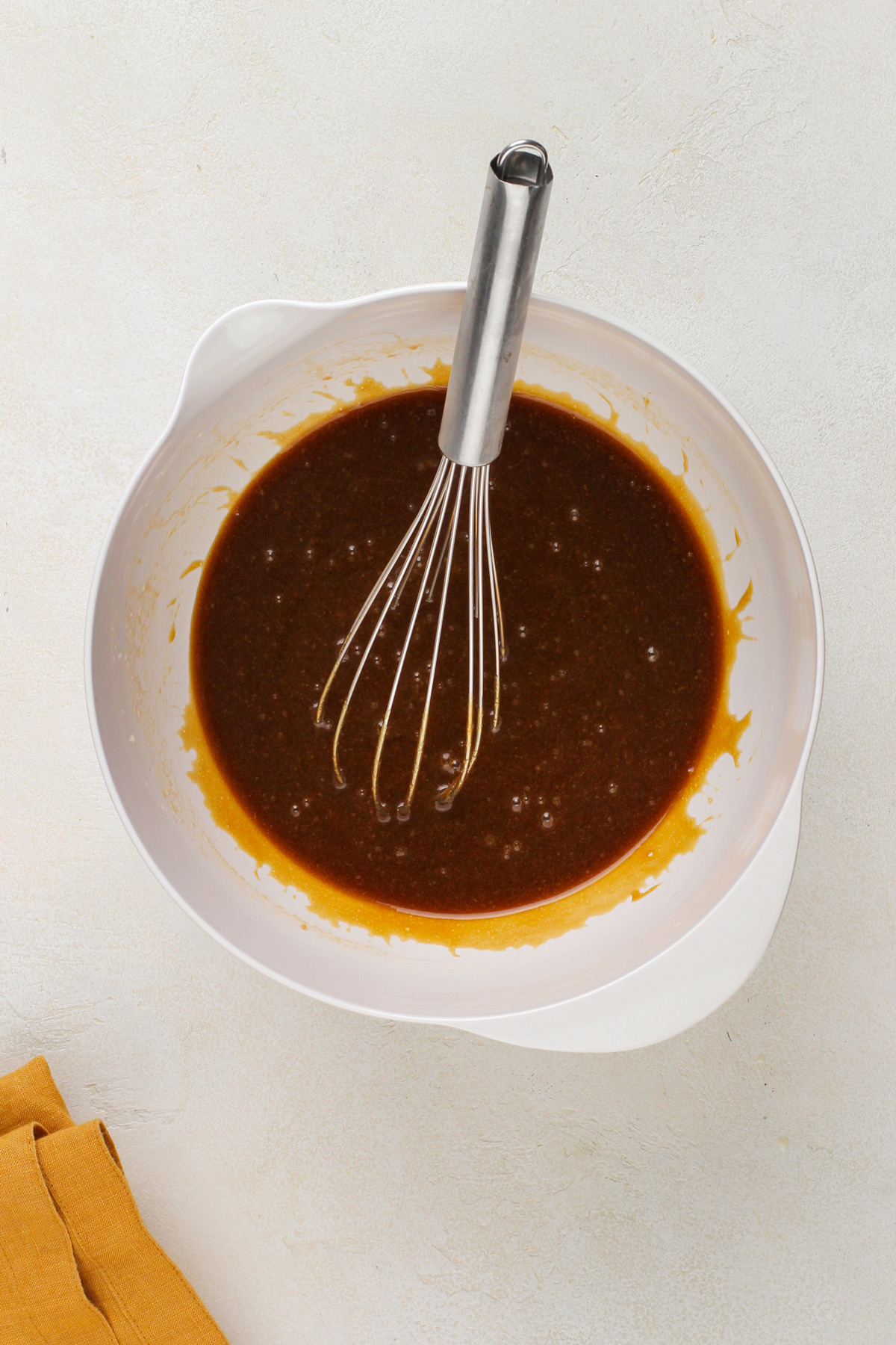 Molasses cookie wet ingredients whisked in a white bowl.