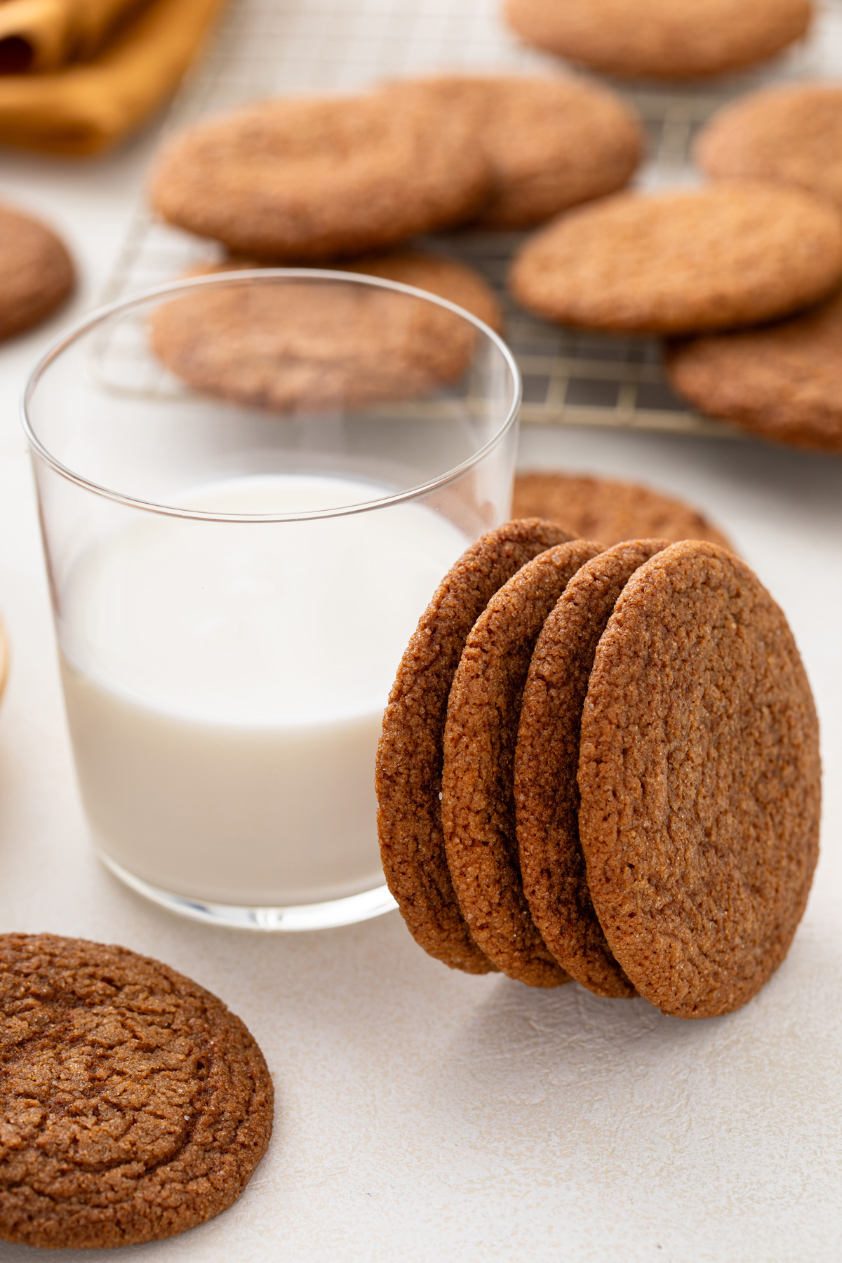 Four molasses cookies leaning against a glass of milk.