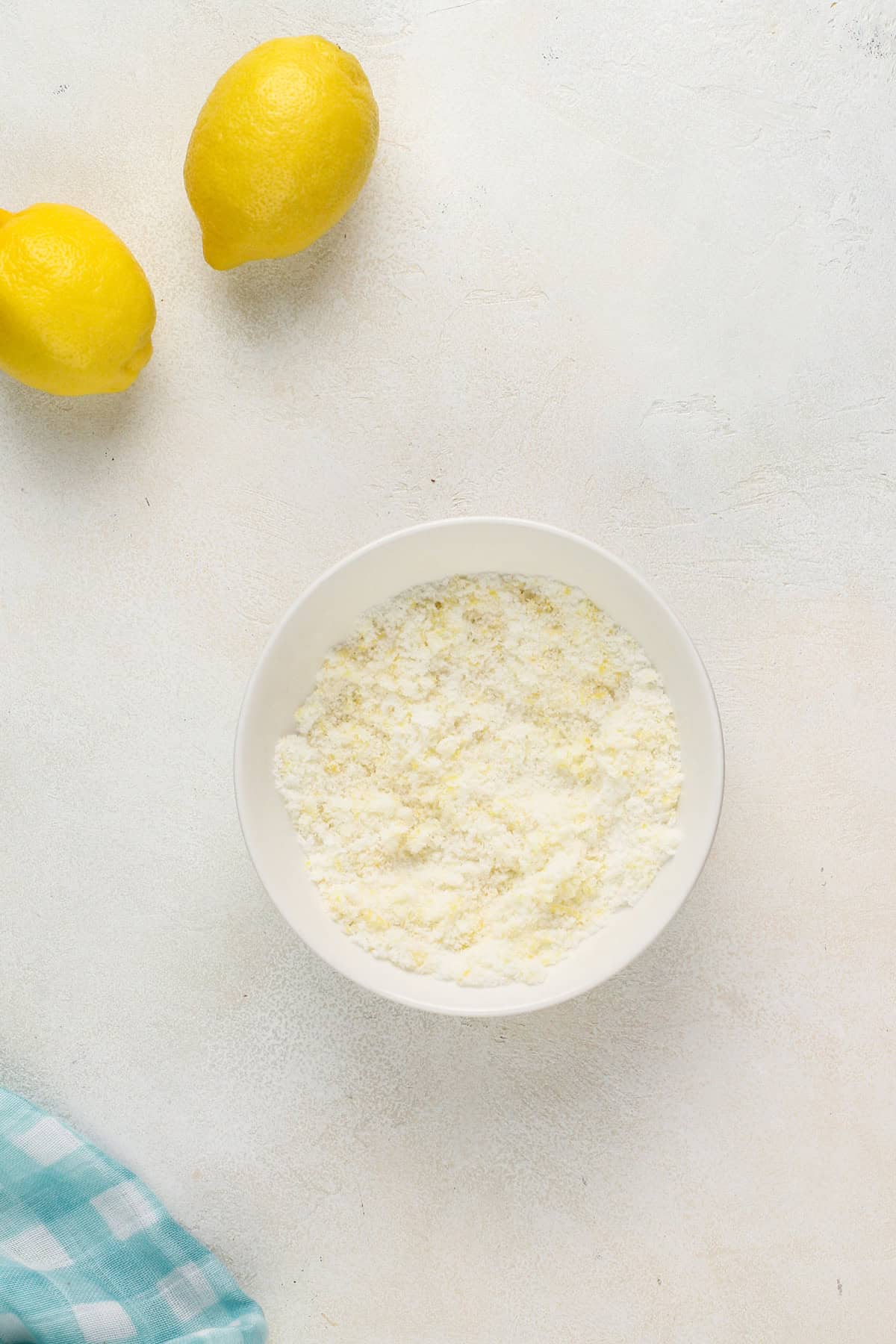 Granulated sugar mixed with lemon zest in a white bowl.