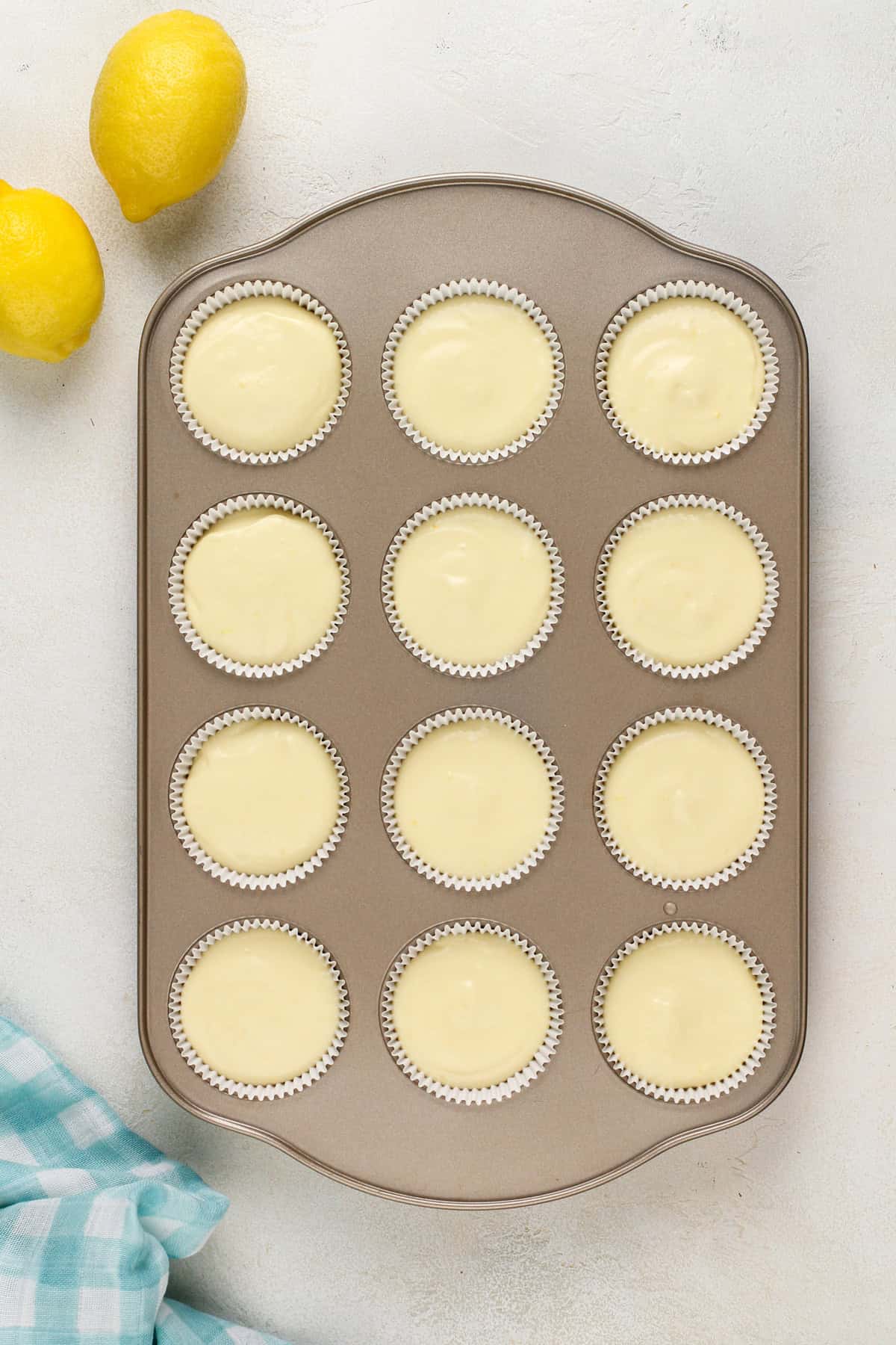 Unbaked mini lemon cheesecakes in a muffin tin, ready to go in the oven.