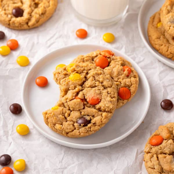 Two reese's pieces cookies on a white plate.