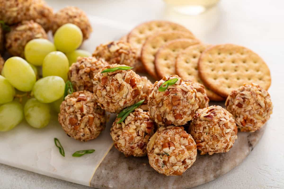 Close up of mini cheese balls next to grapes and crackers.