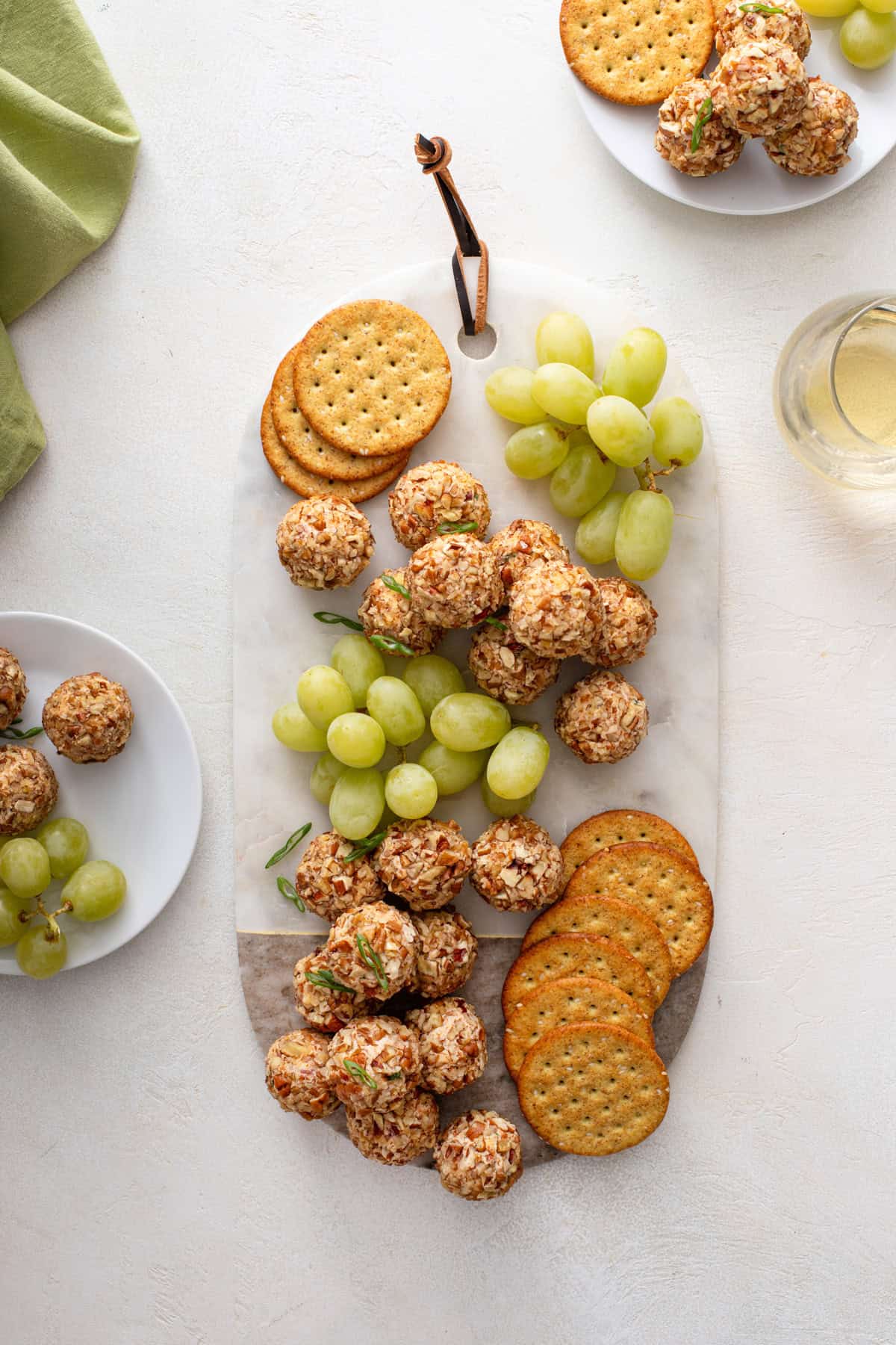 Overhead view of mini cheese balls on a marble board with grapes and crackers.