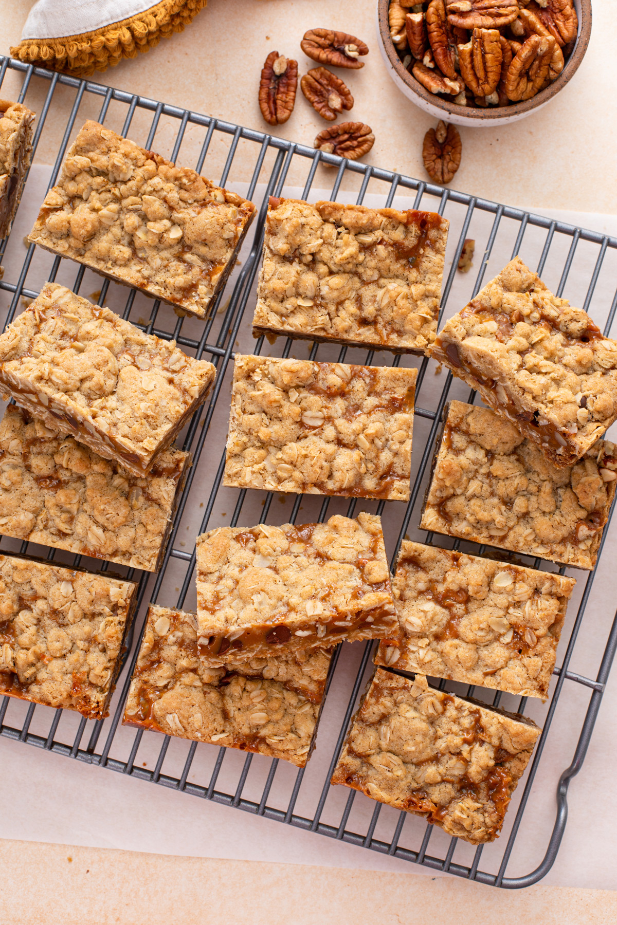 Overhead view of sliced caramel pecan bars arranged on a wire rack.