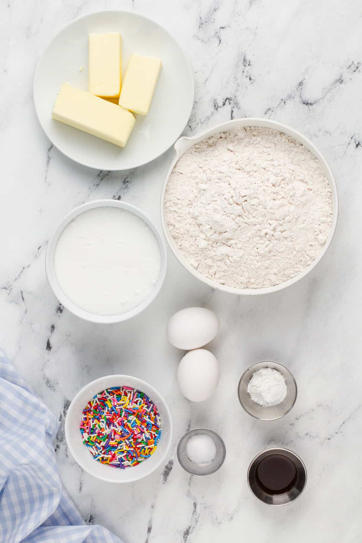 Ingredients for birthday cake cookies arranged on a marble countertop.