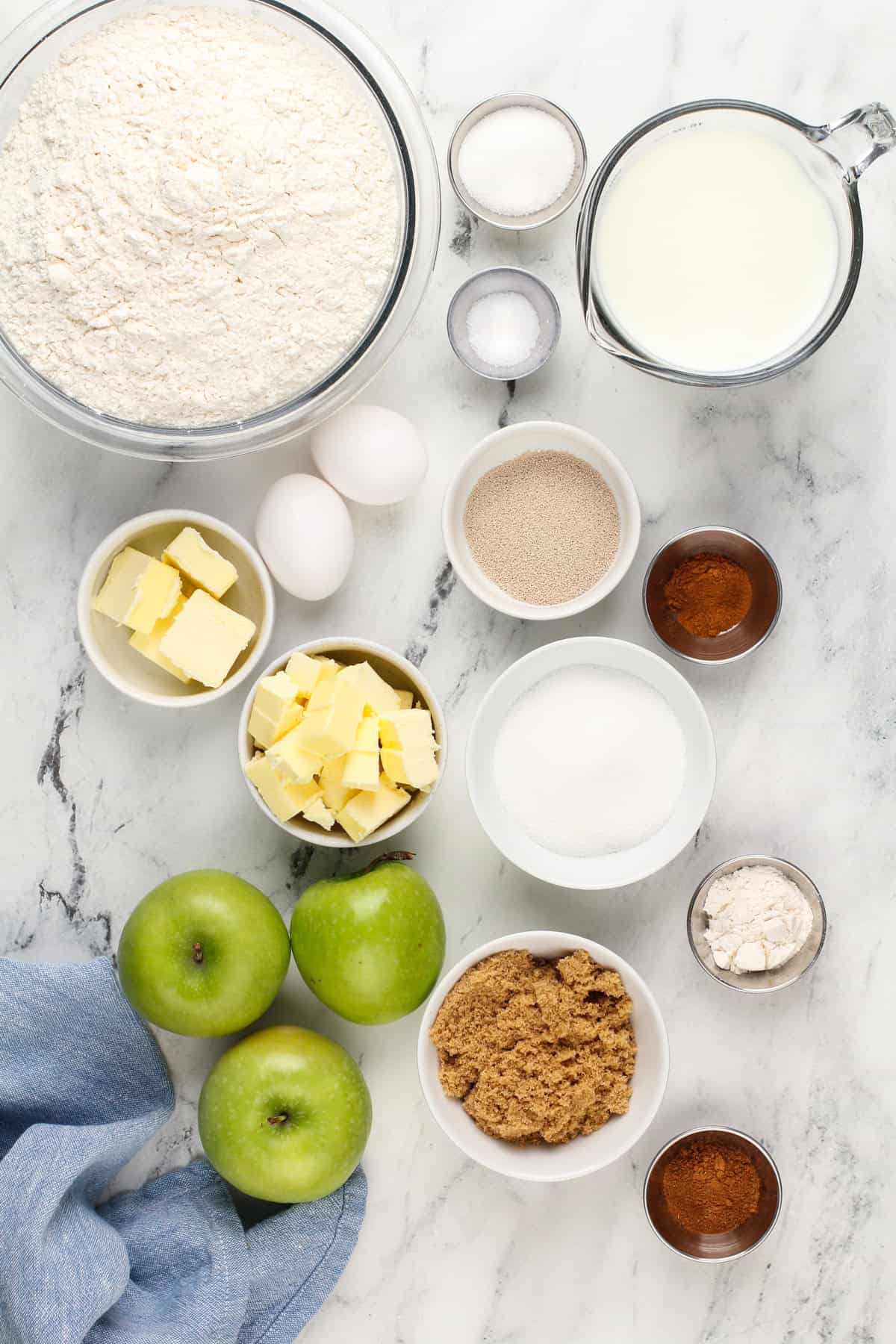 Ingredients for caramel apple cinnamon rolls on a countertop.