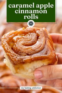 Hand holding up a caramel apple cinnamon roll. Text overlay includes recipe name.