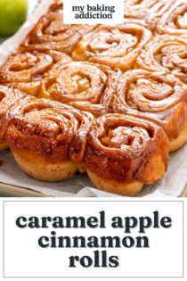 Caramel apple cinnamon rolls on piece of parchment paper on a sheet pan. Text overlay includes recipe name.