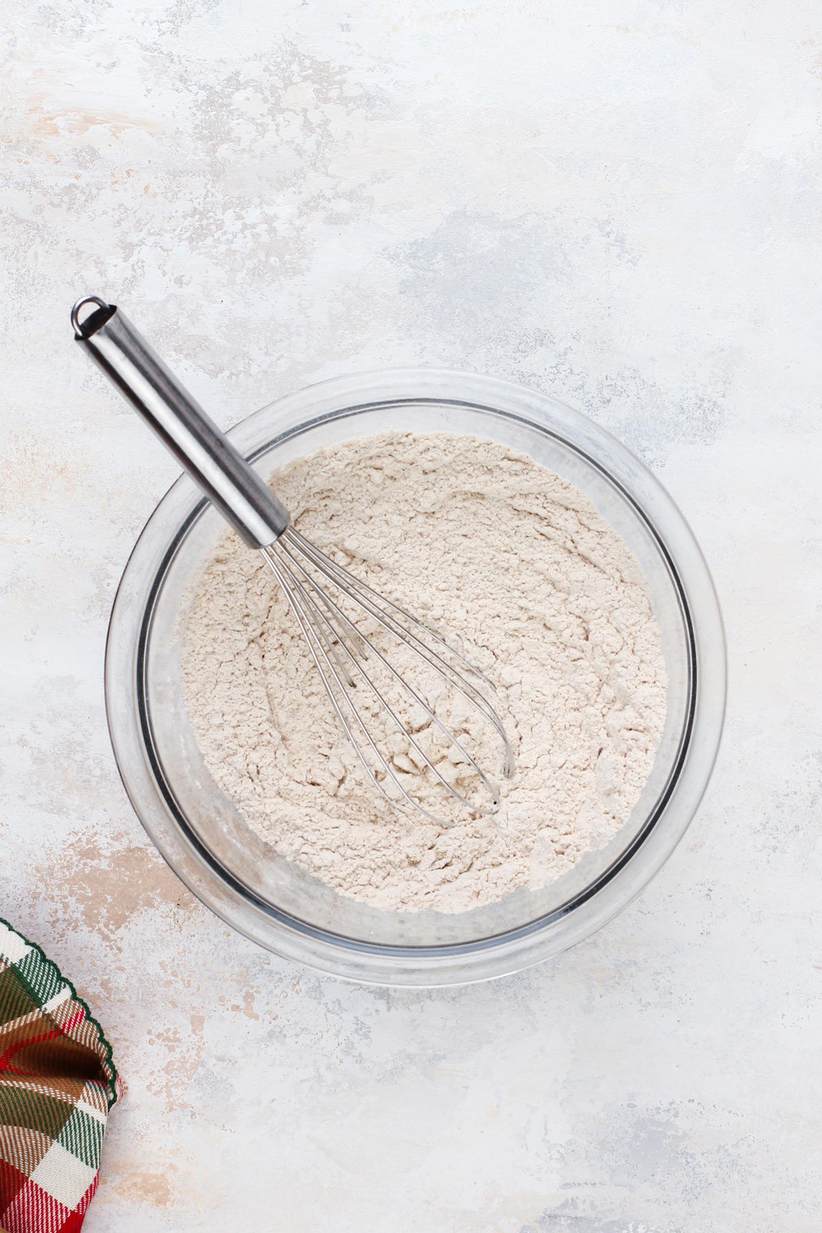 Dry ingredients for gingersnaps being whisked in a glass bowl.