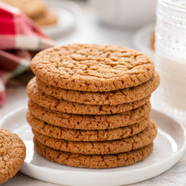 Stacked gingersnap cookies on a white plate.