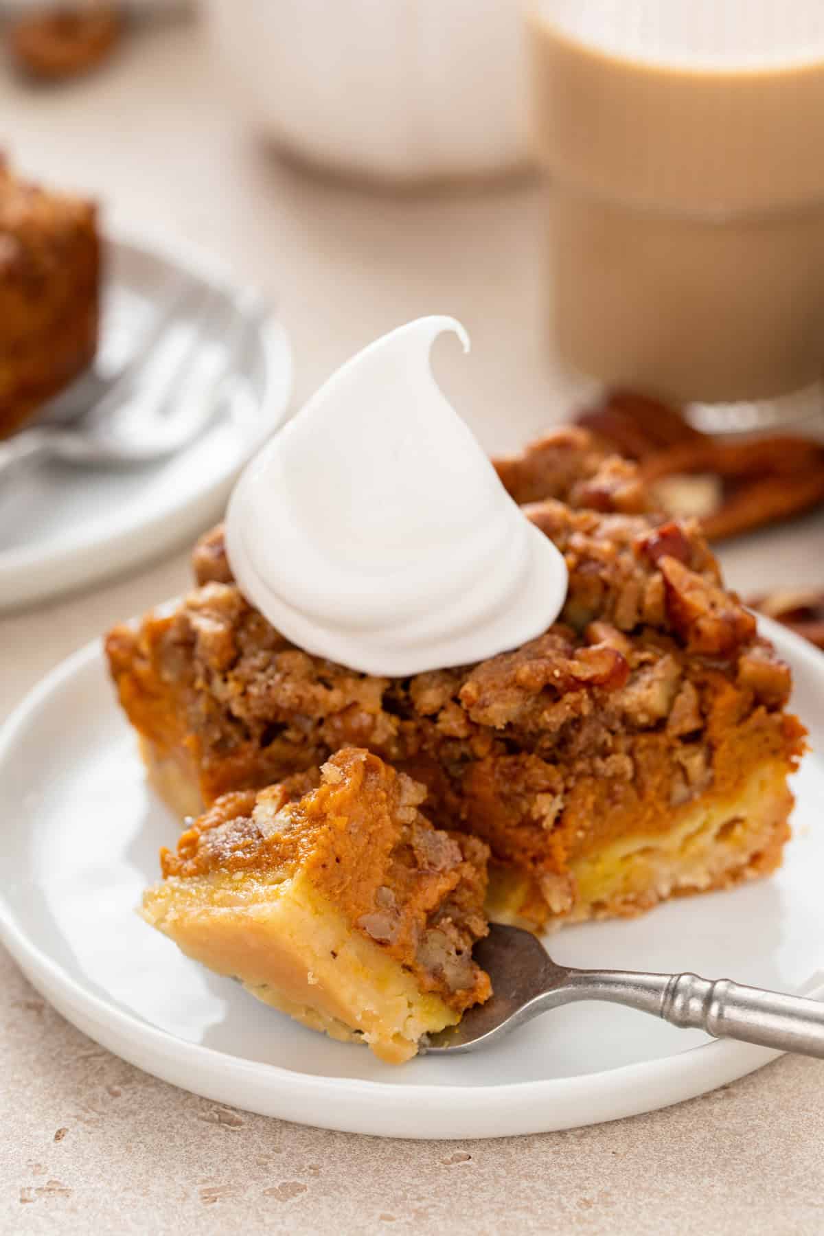 Fork cutting a bite from the corner of a plated pumpkin pecan pie bar.