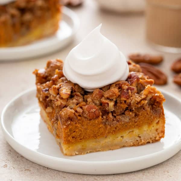 Plated pumpkin pecan pie bar with a dollop of whipped cream on top.