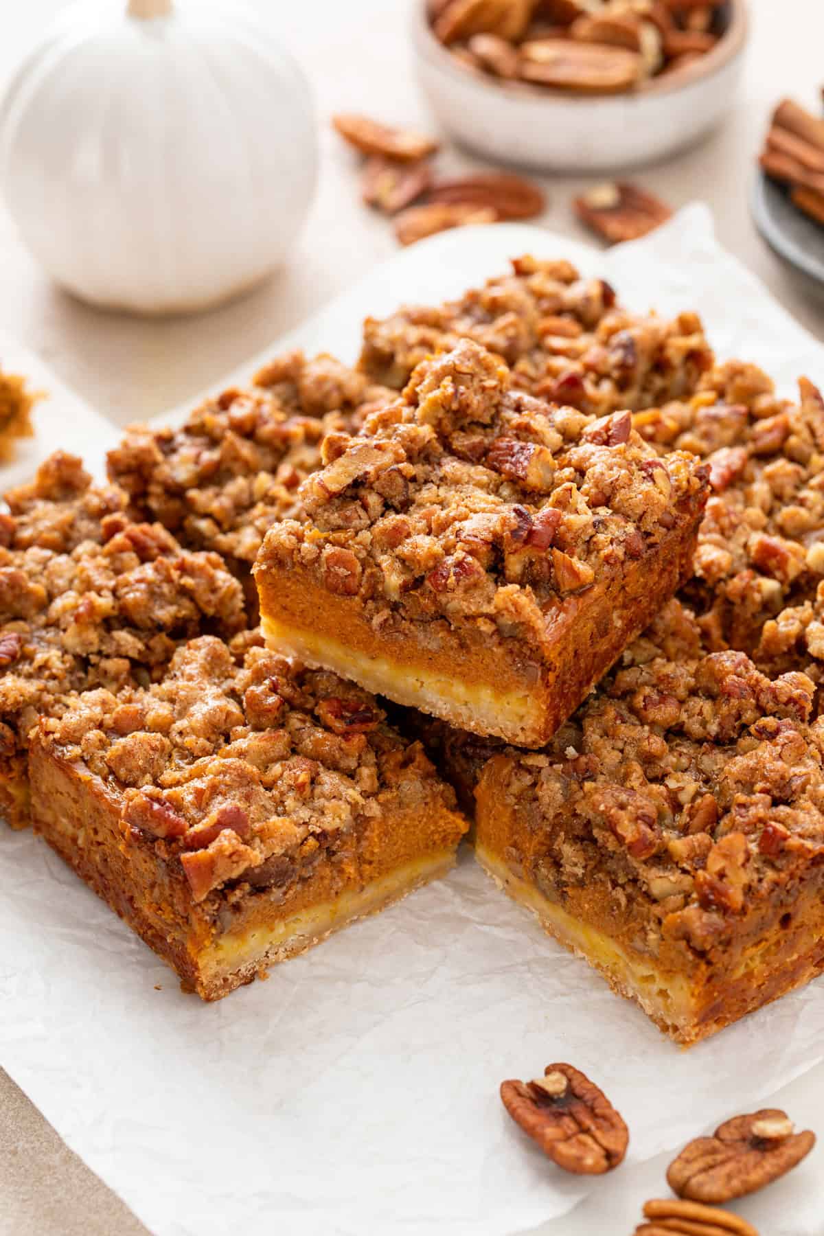 Sliced pumpkin pecan pie bars arranged on a piece of parchment paper.