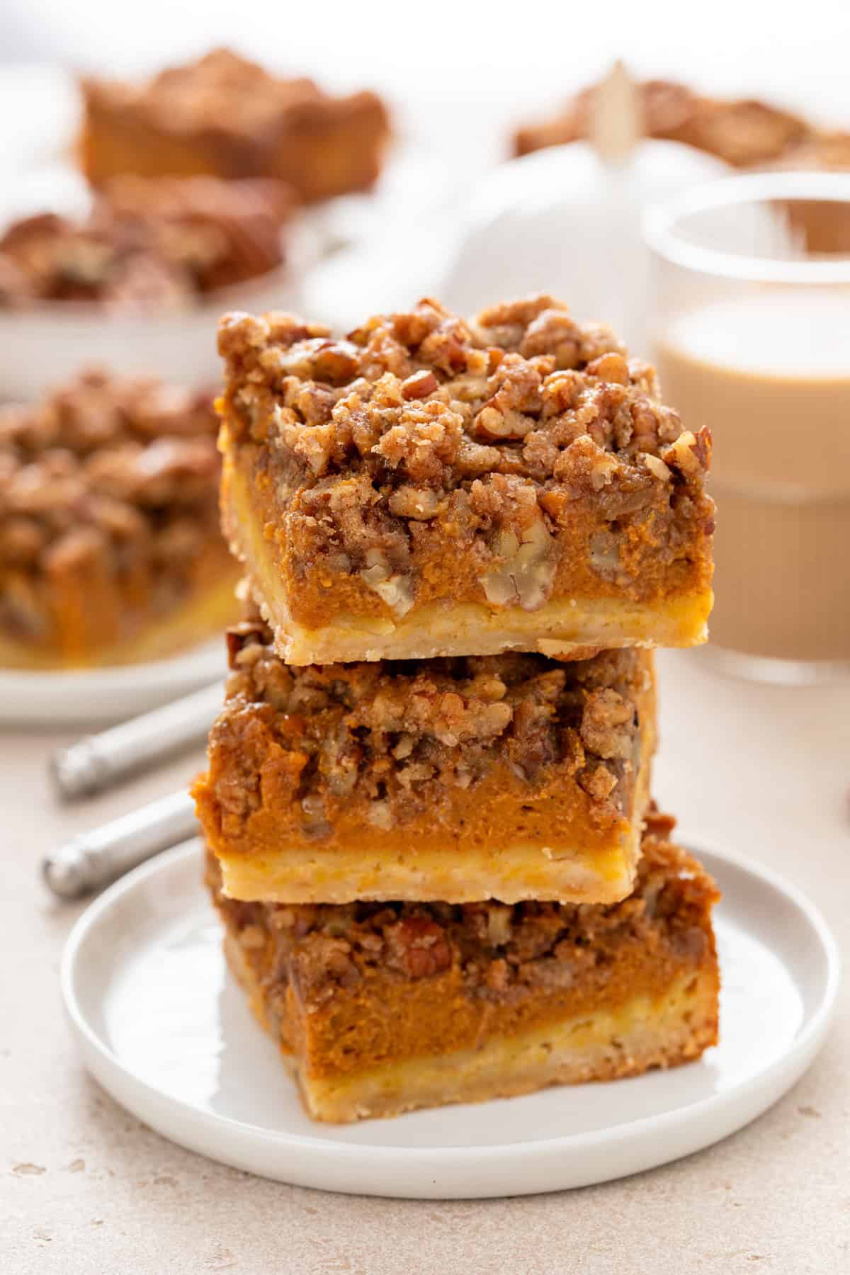 Three pumpkin pecan pie bars stacked on a white plate.