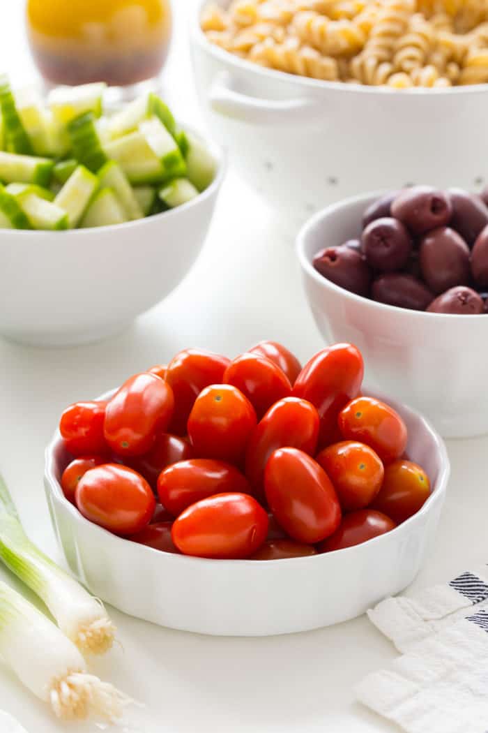 Close up of a bowl of grape tomatoes with other veggies in the background