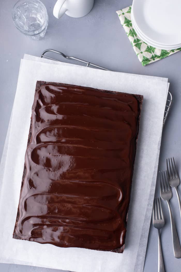 Frosted chocolate zucchini cake on a piece of parchment paper.