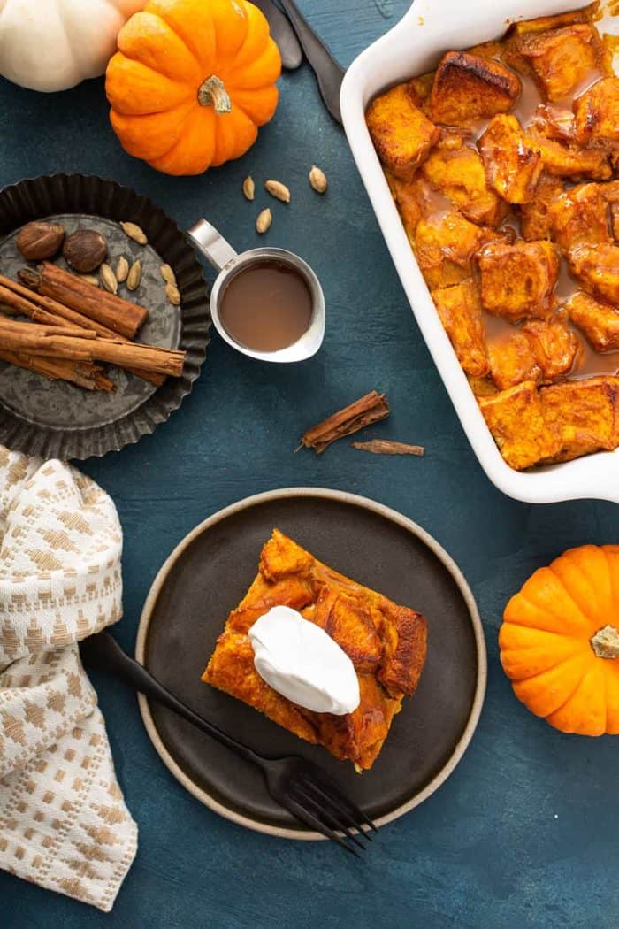Overhead view of a plated slice of bread pudding next to a baking dish of pumpkin bread pudding