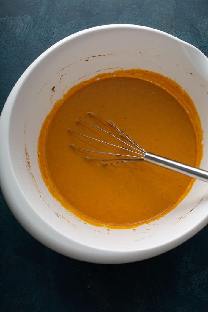 Pumpkin custard being whisked together in a white bowl