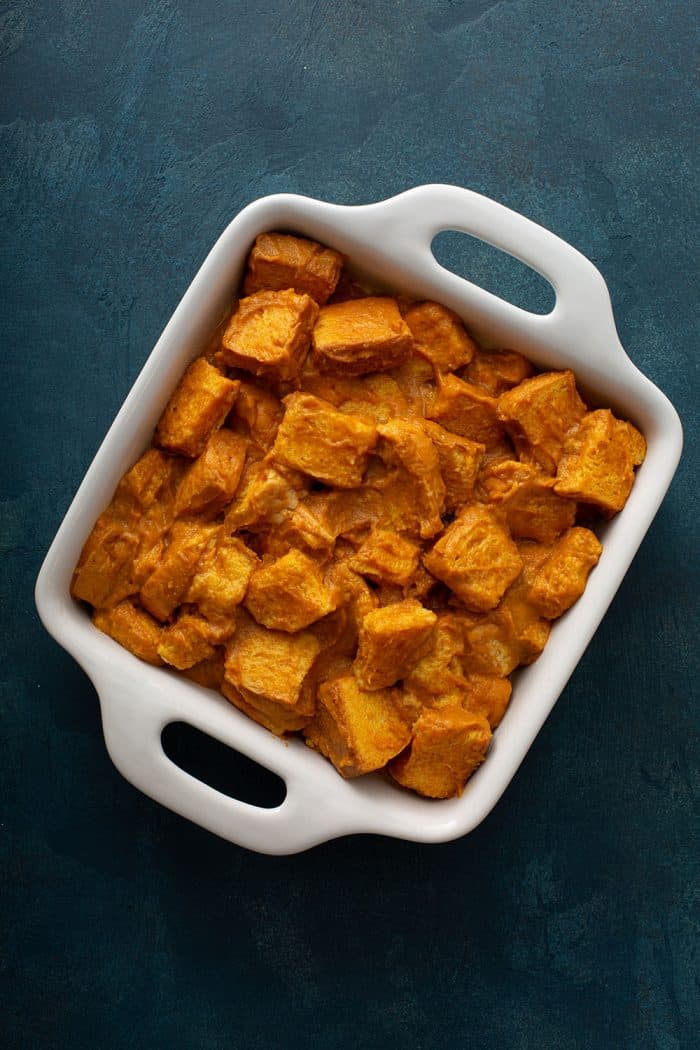 Pumpkin bread pudding in a white baking dish, ready to be baked