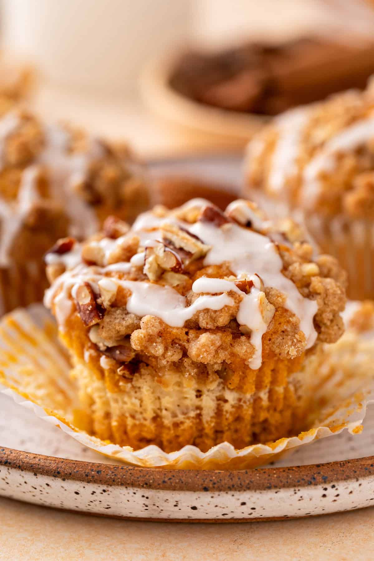 Pumpkin cream cheese muffin on a plate. The muffin's wrapper is unwrapped.