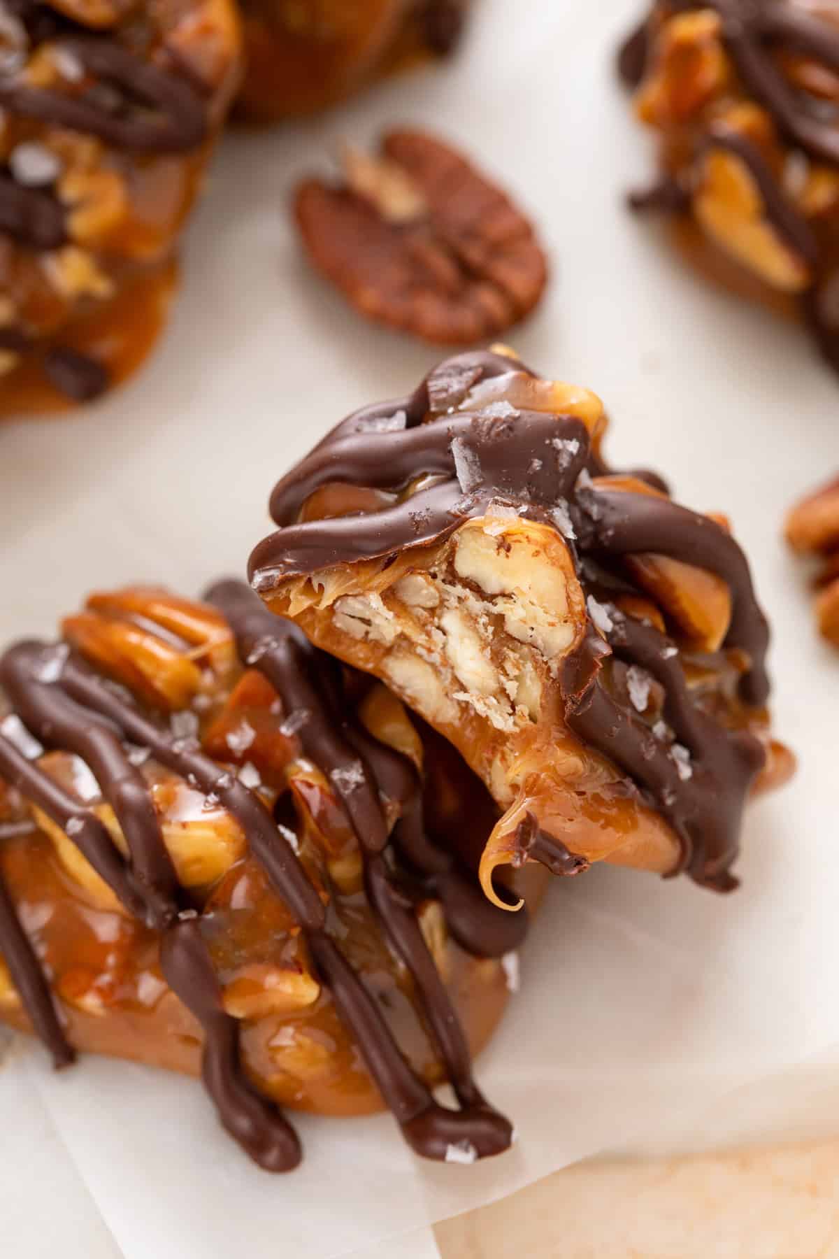 Close up of two pecan caramel clusters, with a bite taken from one of them.