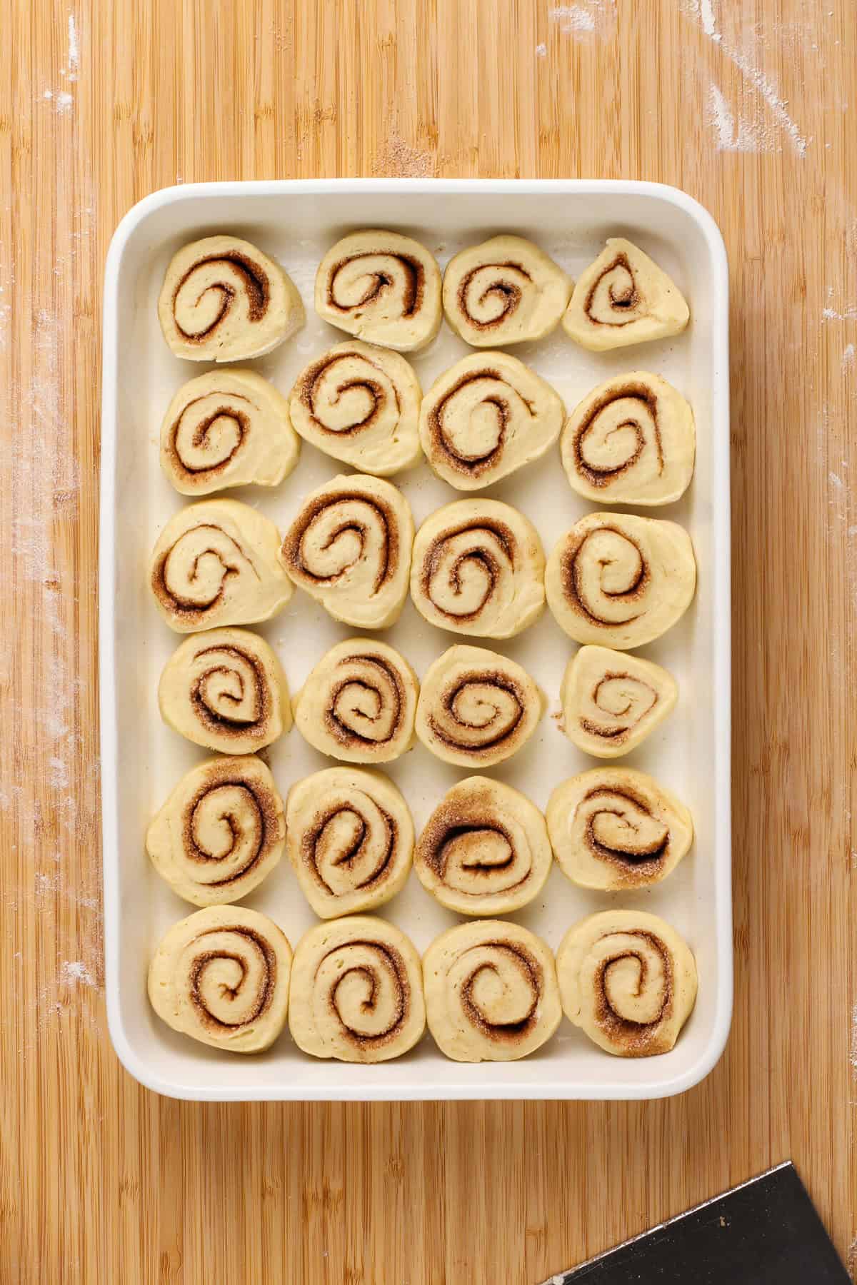 Sliced and unbaked mini cinnamon rolls in a white baking dish.