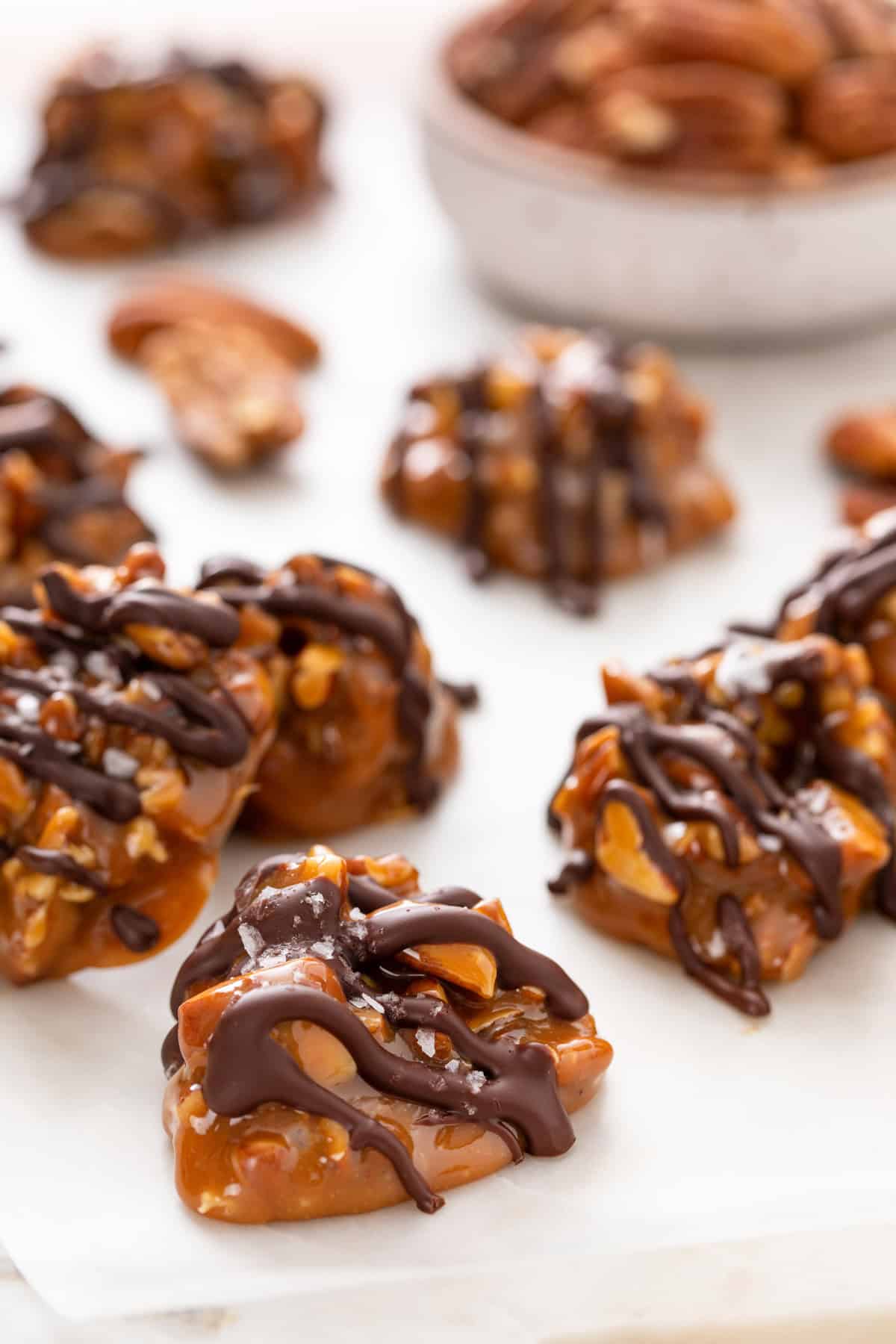 Close up of pecan caramel clusters on a parchment-lined board.