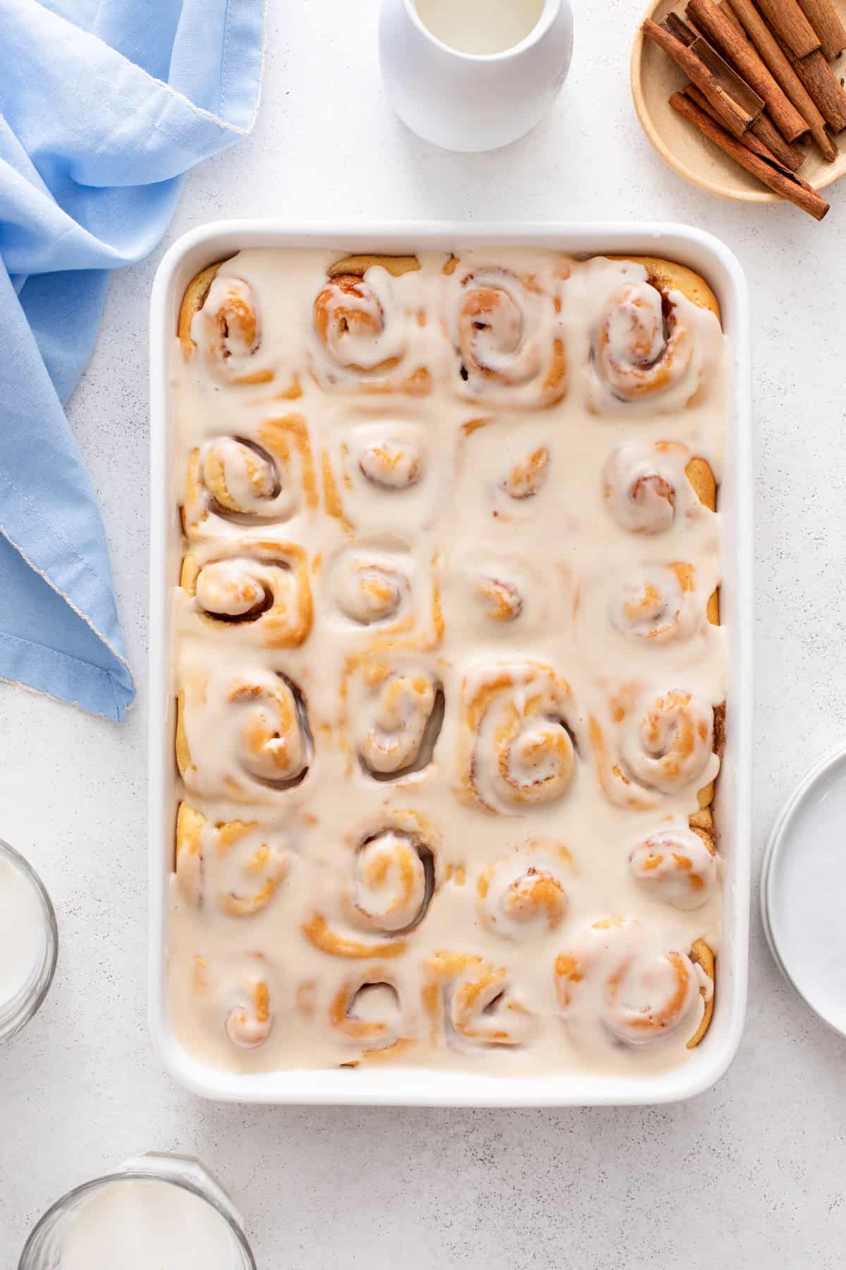 Mini cinnamon rolls topped with glaze in a ceramic baking dish.