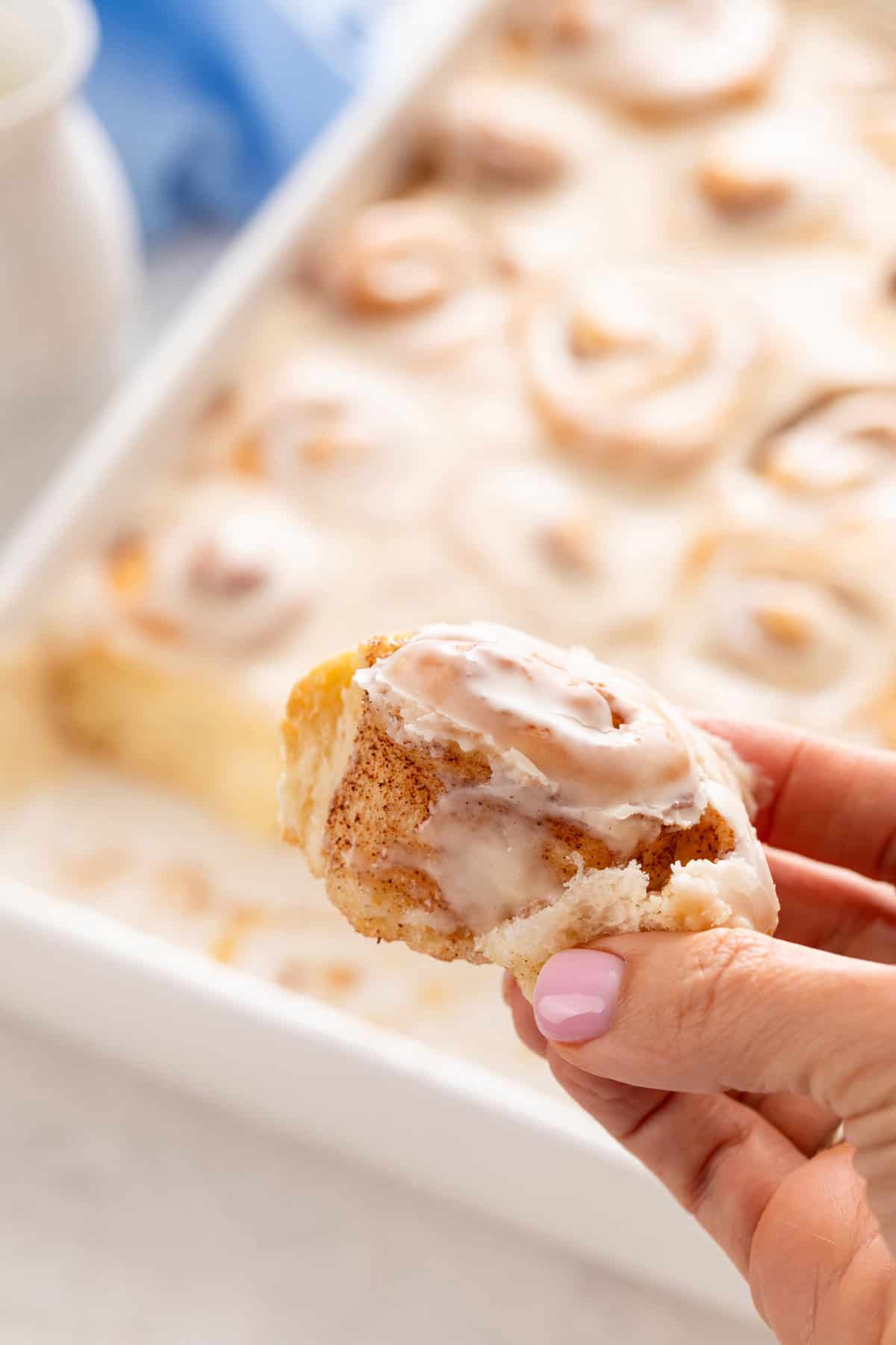 Hand holding up a mini cinnamon roll.