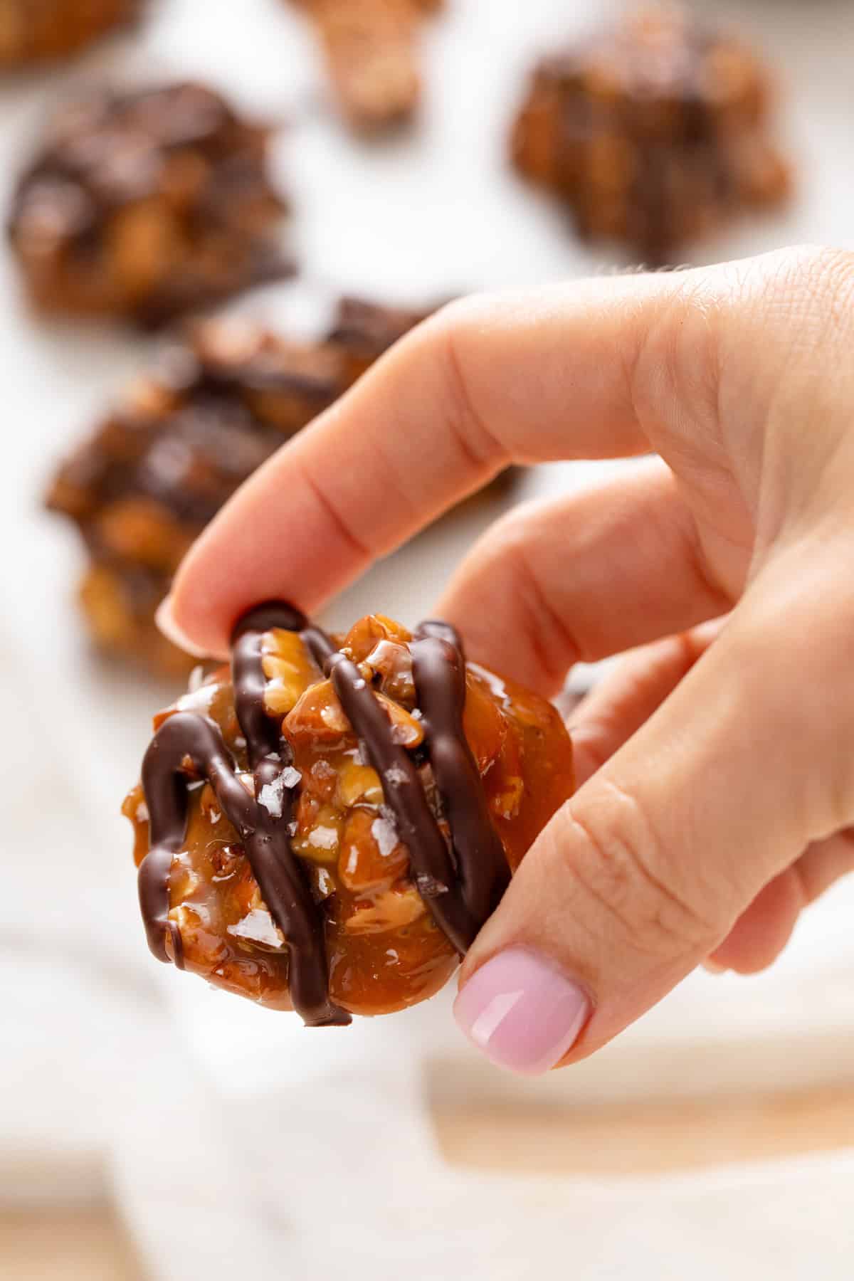 Hand holding up a pecan caramel cluster.