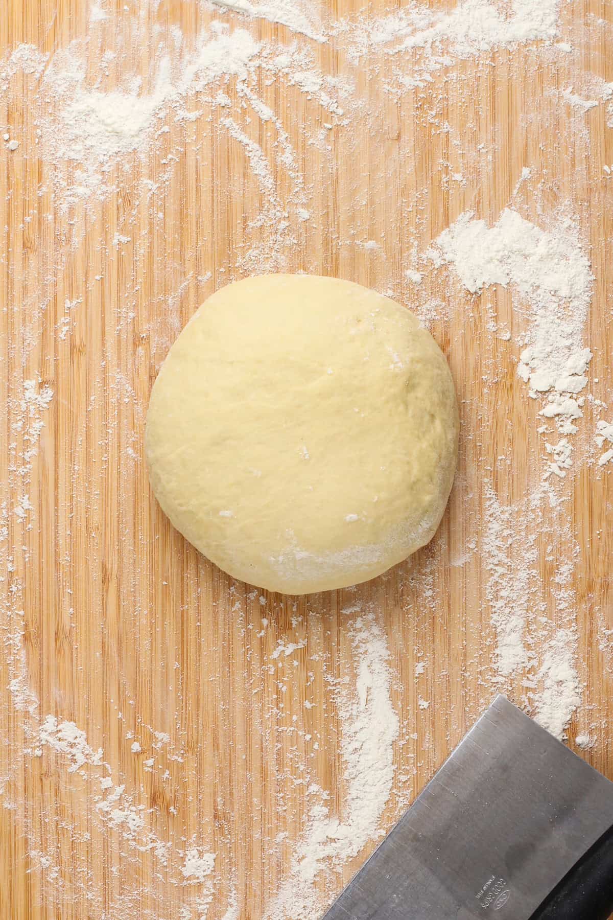 Kneaded cinnamon roll dough on a wooden board.