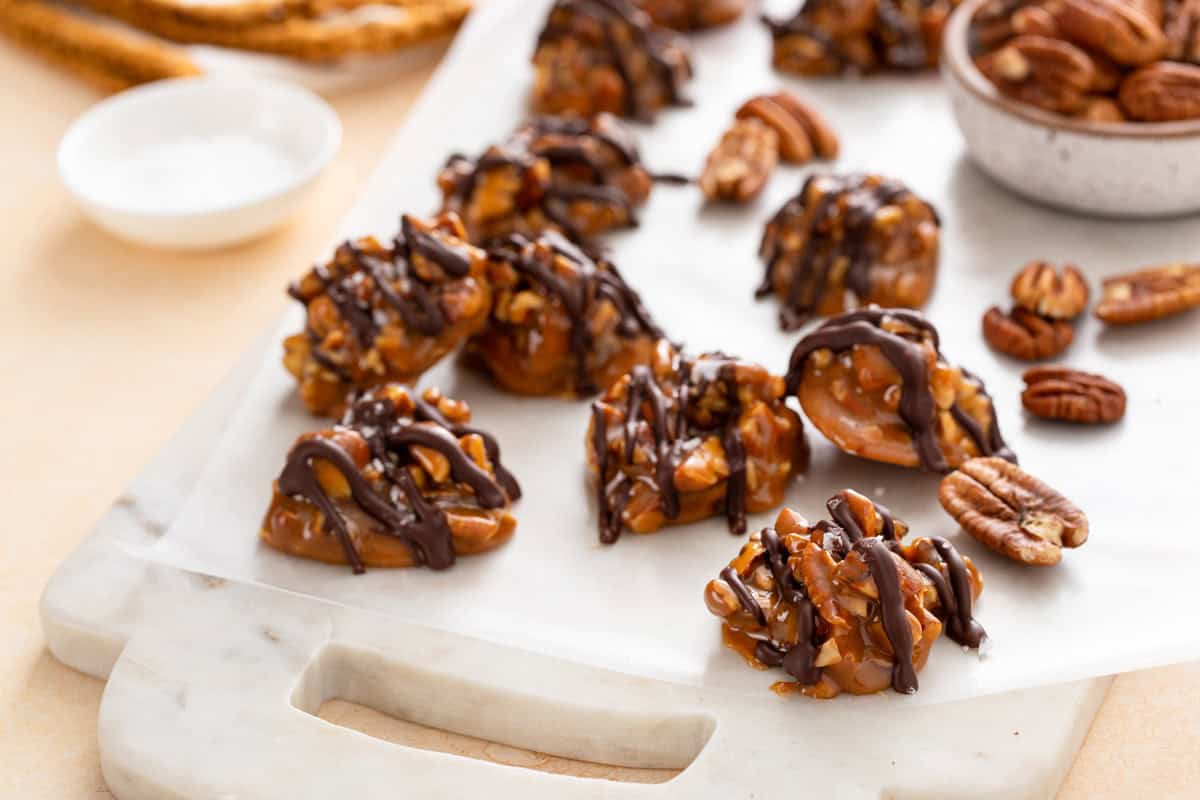 Pecan caramel clusters scattered on a marble cutting board.