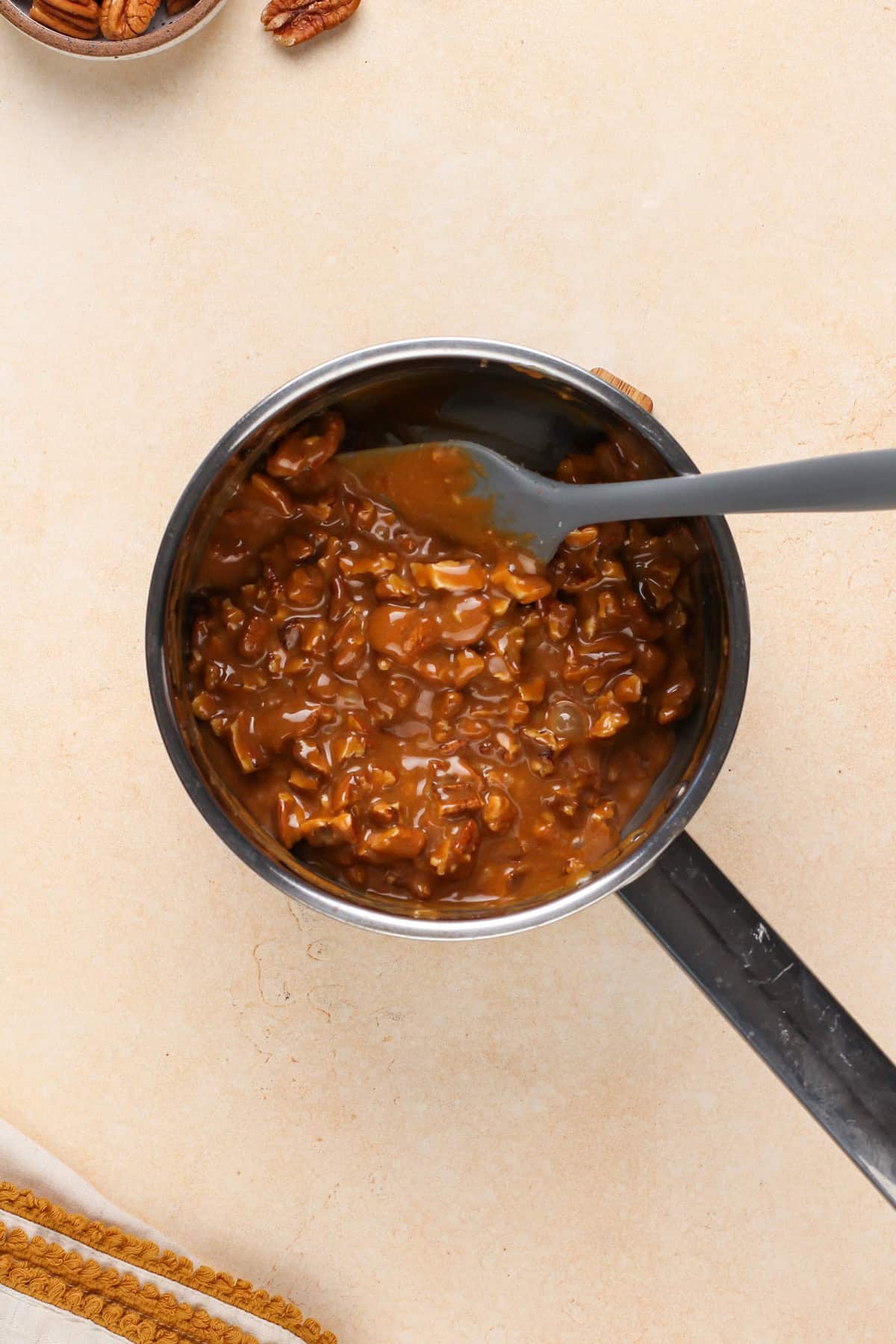 Pecan caramel mixture stirred together in a saucepan.