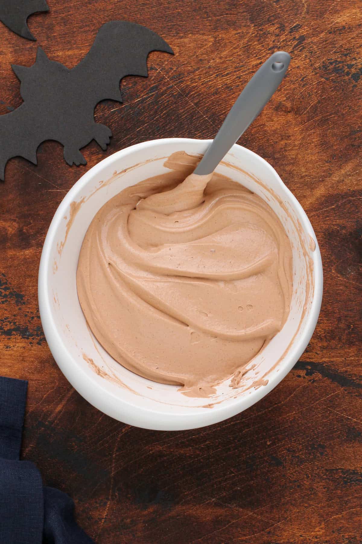 Cool whip folded into chocolate pudding in a mixing bowl.