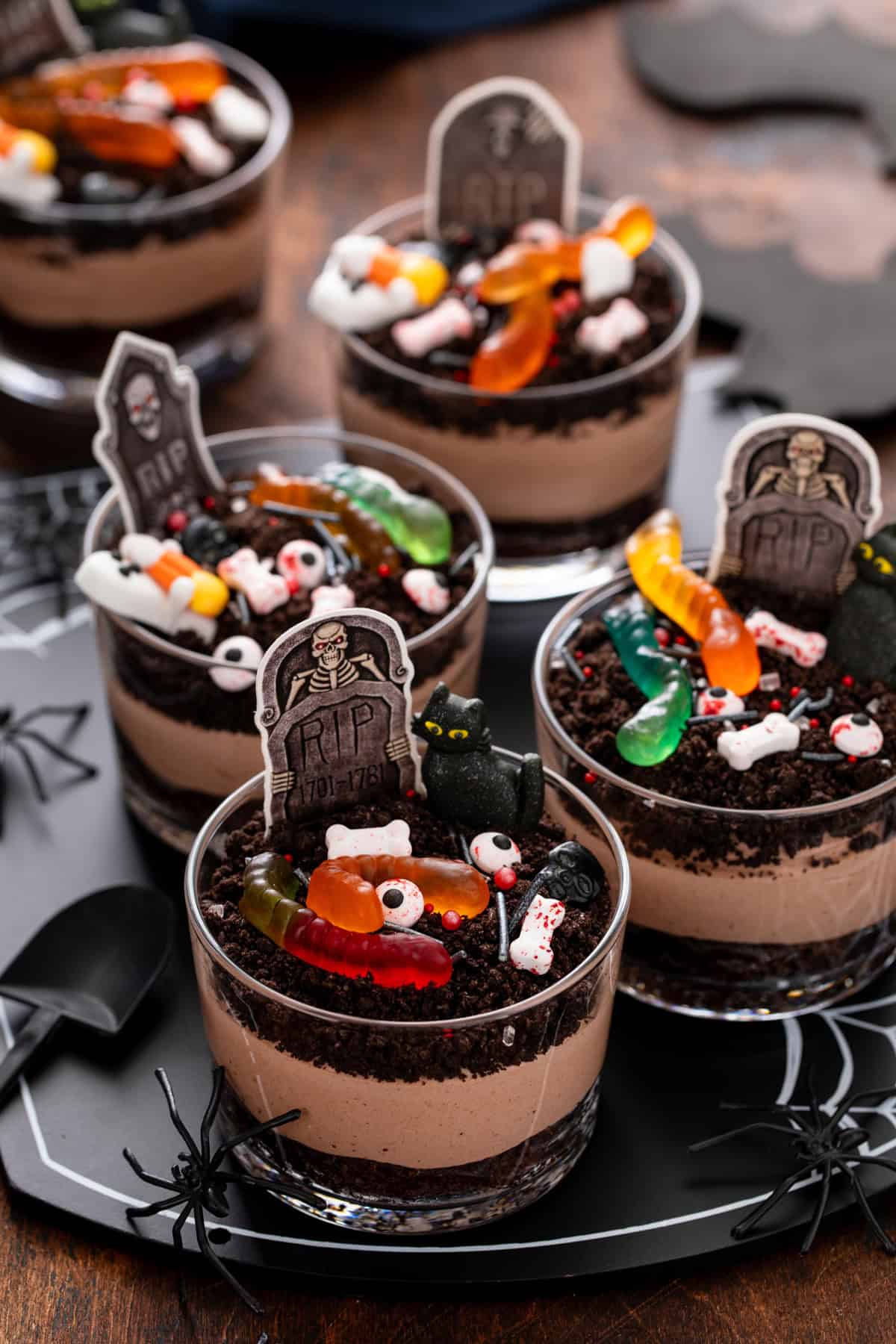 Several decorated brownie dirt puddings arranged on a Halloween themed platter.